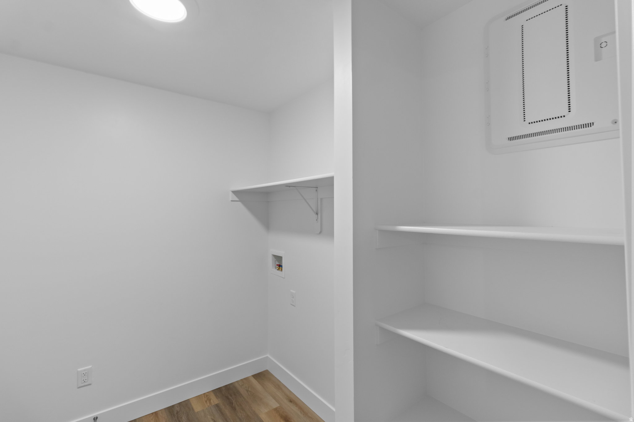 Laundry area featuring wood-finish flooring, a wall-mounted shelf, and connections for appliances