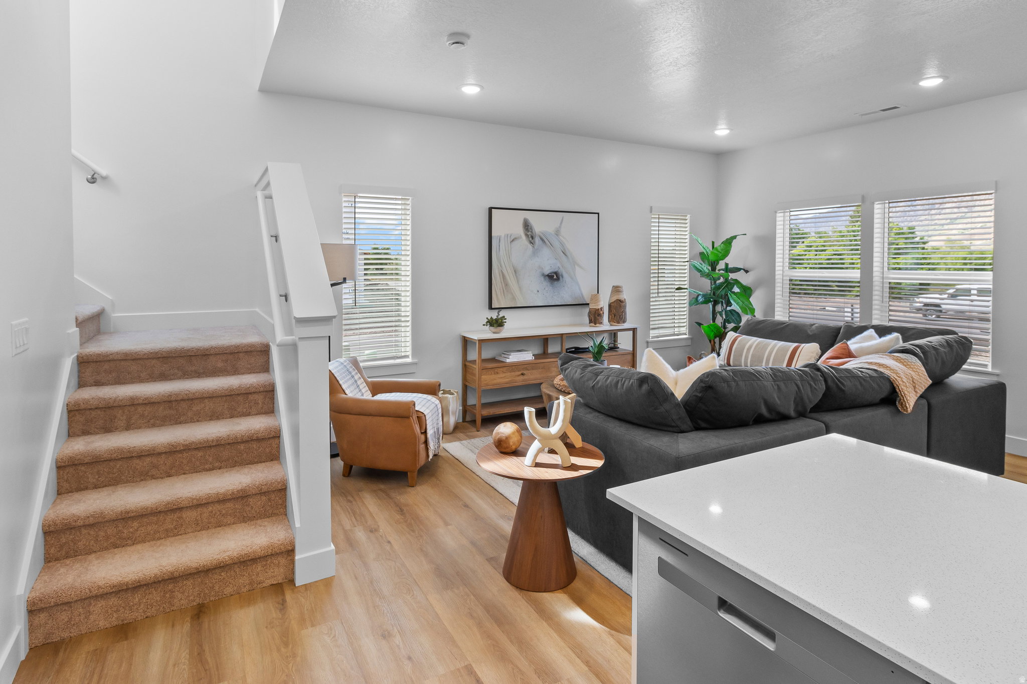 Open-concept living area with light wood-finish flooring, recessed lighting, and multiple windows