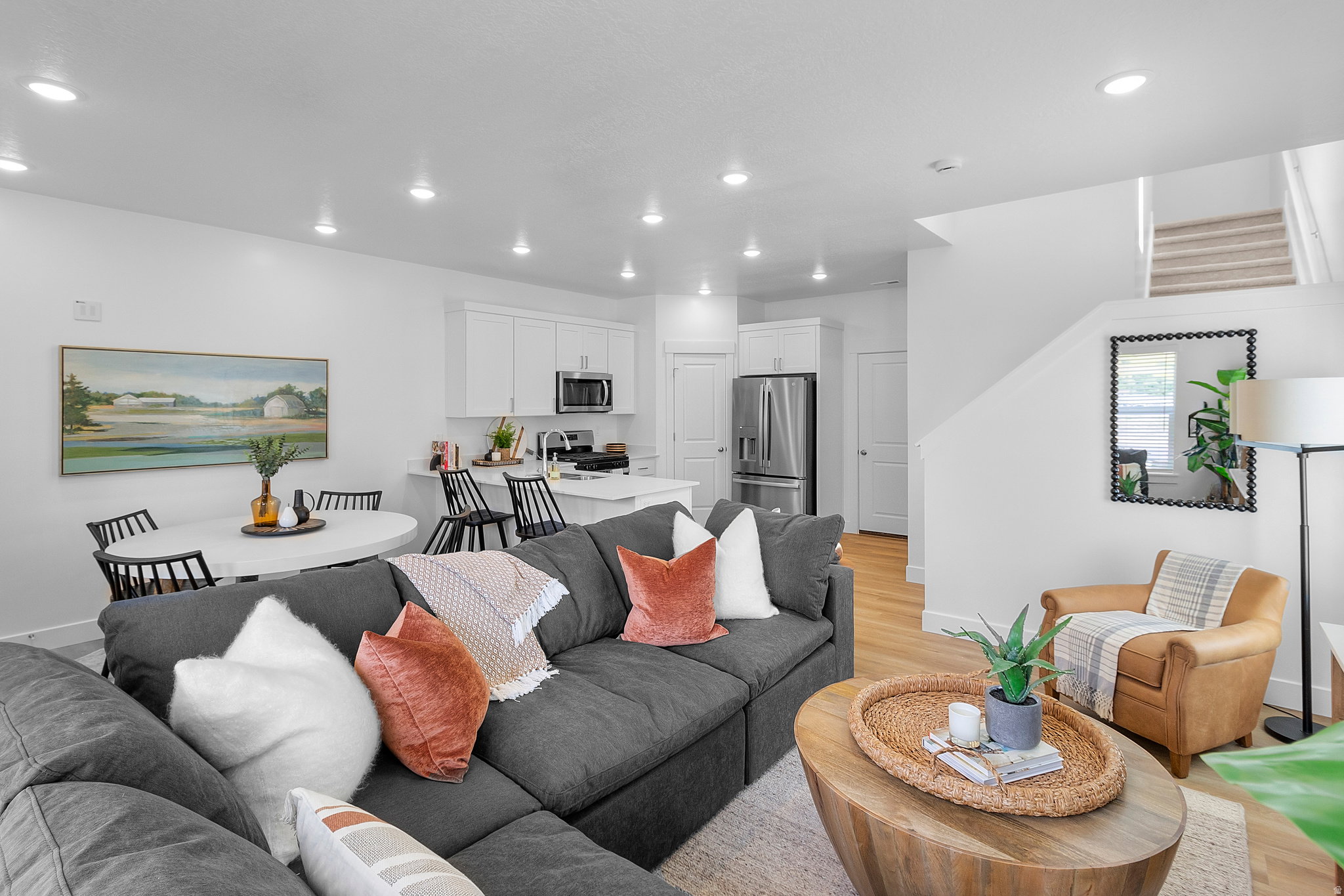 Open-concept living area featuring light wood-finish flooring, recessed lighting, and a white color palette