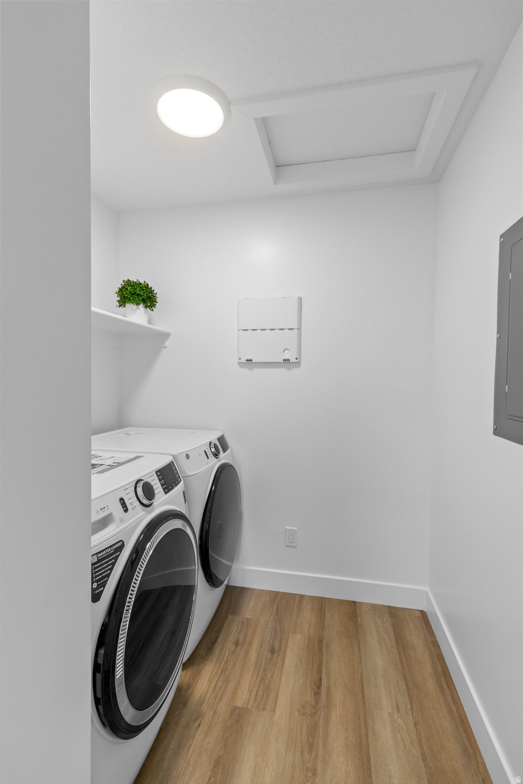 Dedicated utility area featuring wood-finish flooring, a white wall-mounted shelf, and a ceiling-mounted light fixture