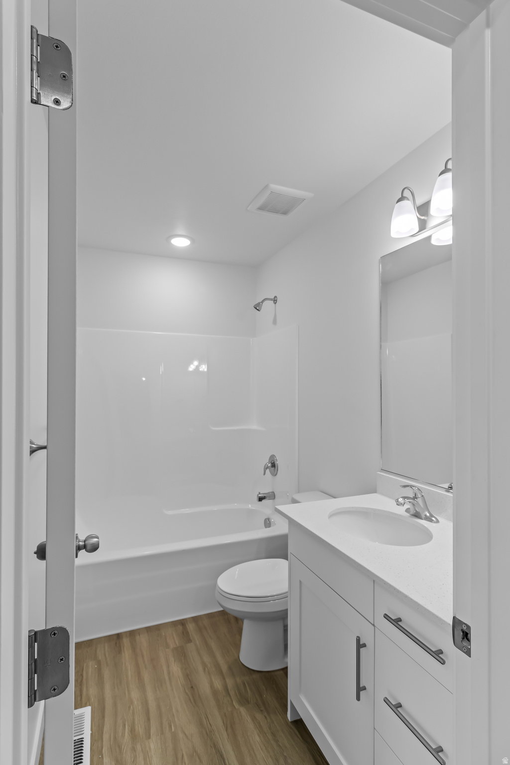 Bathroom featuring a white vanity with integrated sink, chrome faucet, and rectangular mirror