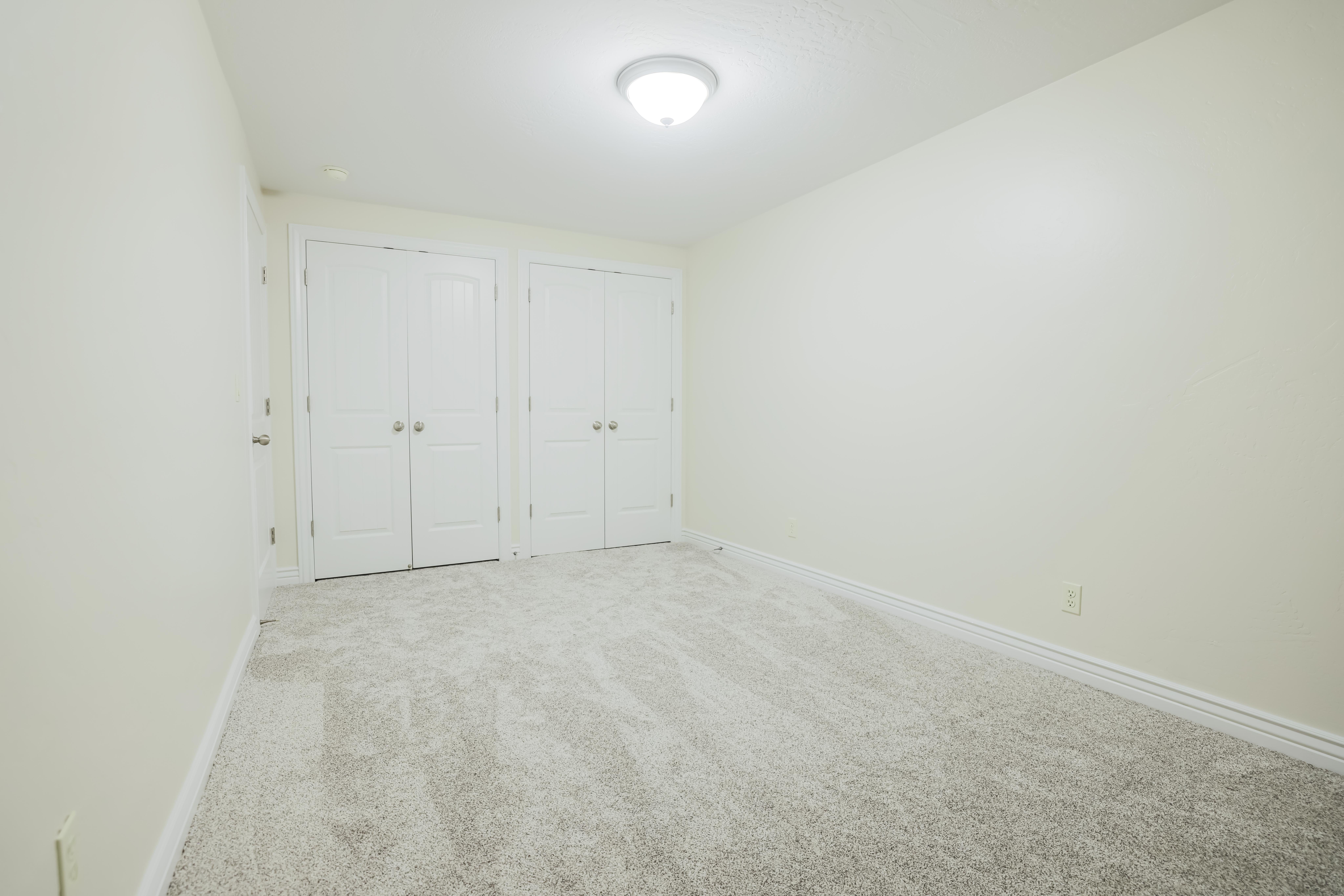 Neutral wall colors, light-toned carpet, and a flush mount ceiling light fixture