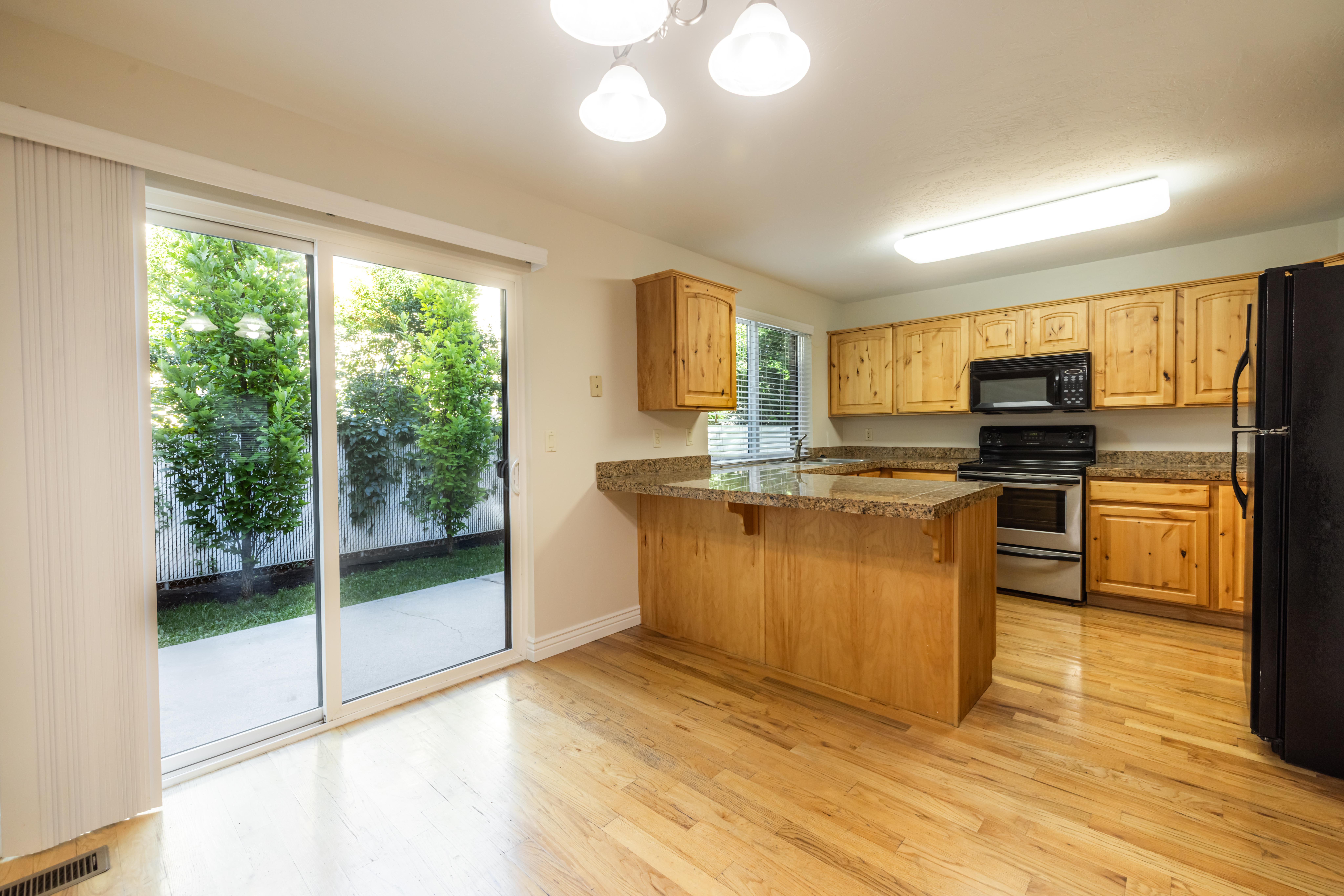 Kitchen featuring wood-finish flooring, a central island with a granite-style countertop, and wood cabinetry
