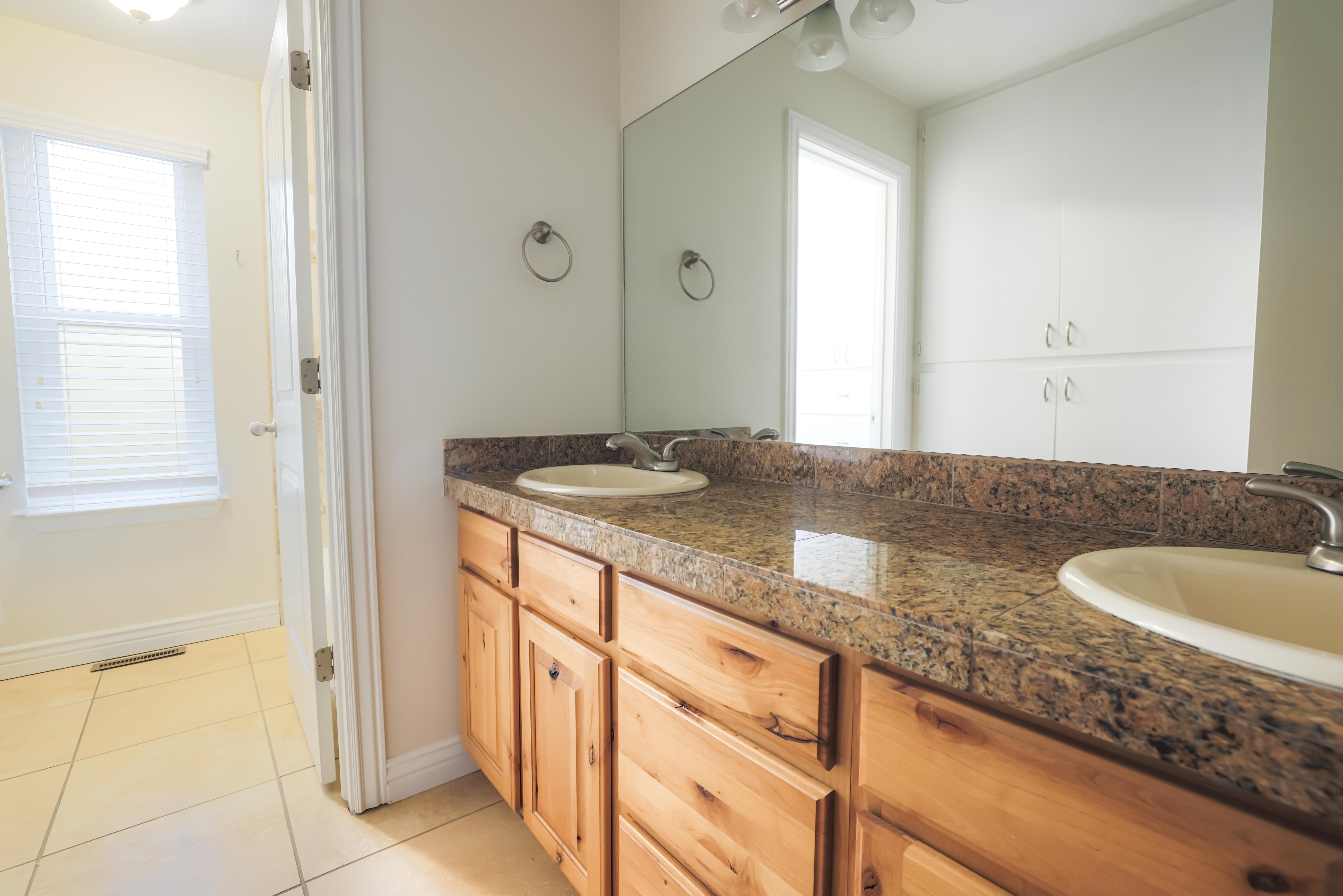 Dual vanity with a stone countertop and light wood cabinetry