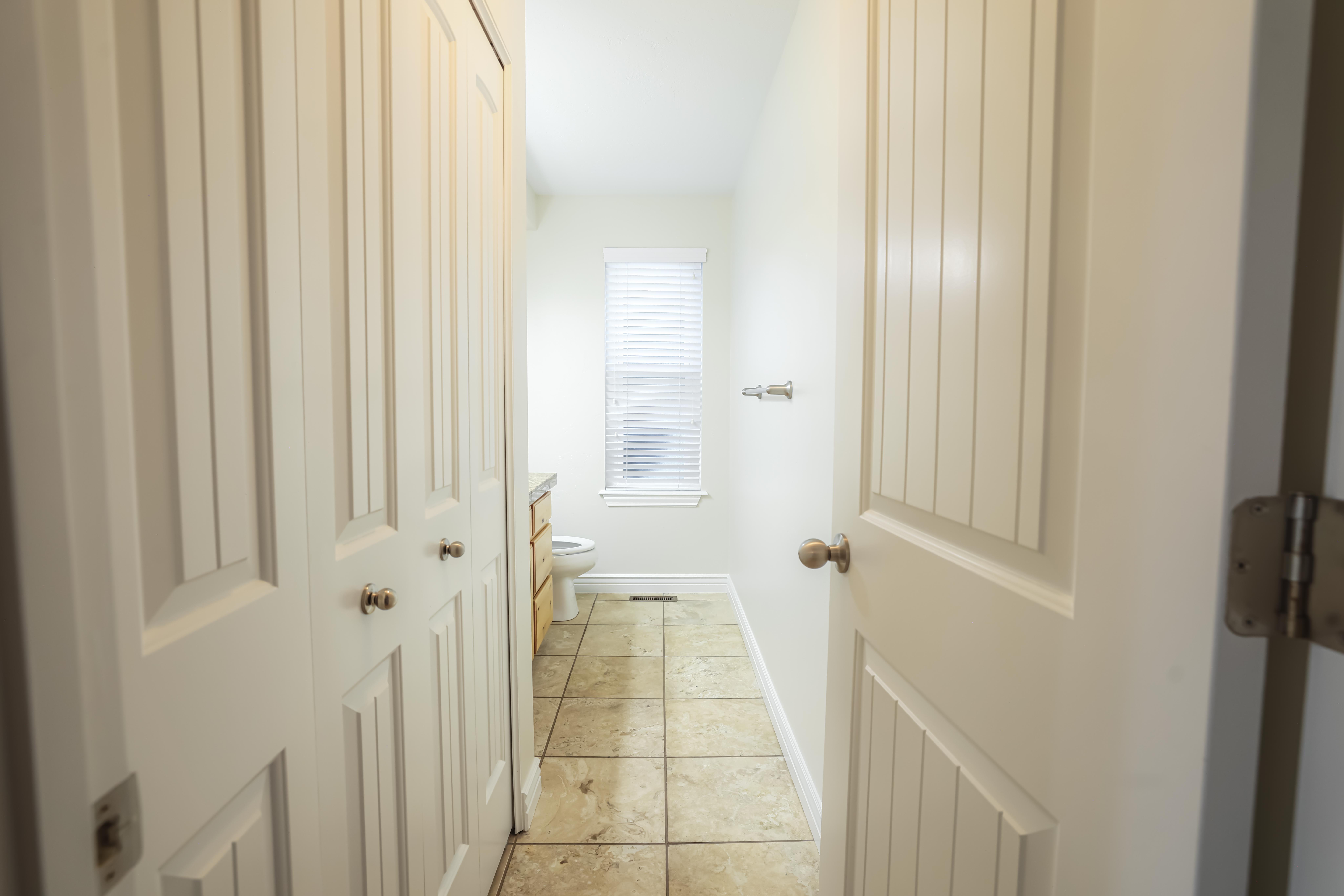 Half-bath featuring white bi-fold closet doors, tile flooring, and light-colored walls