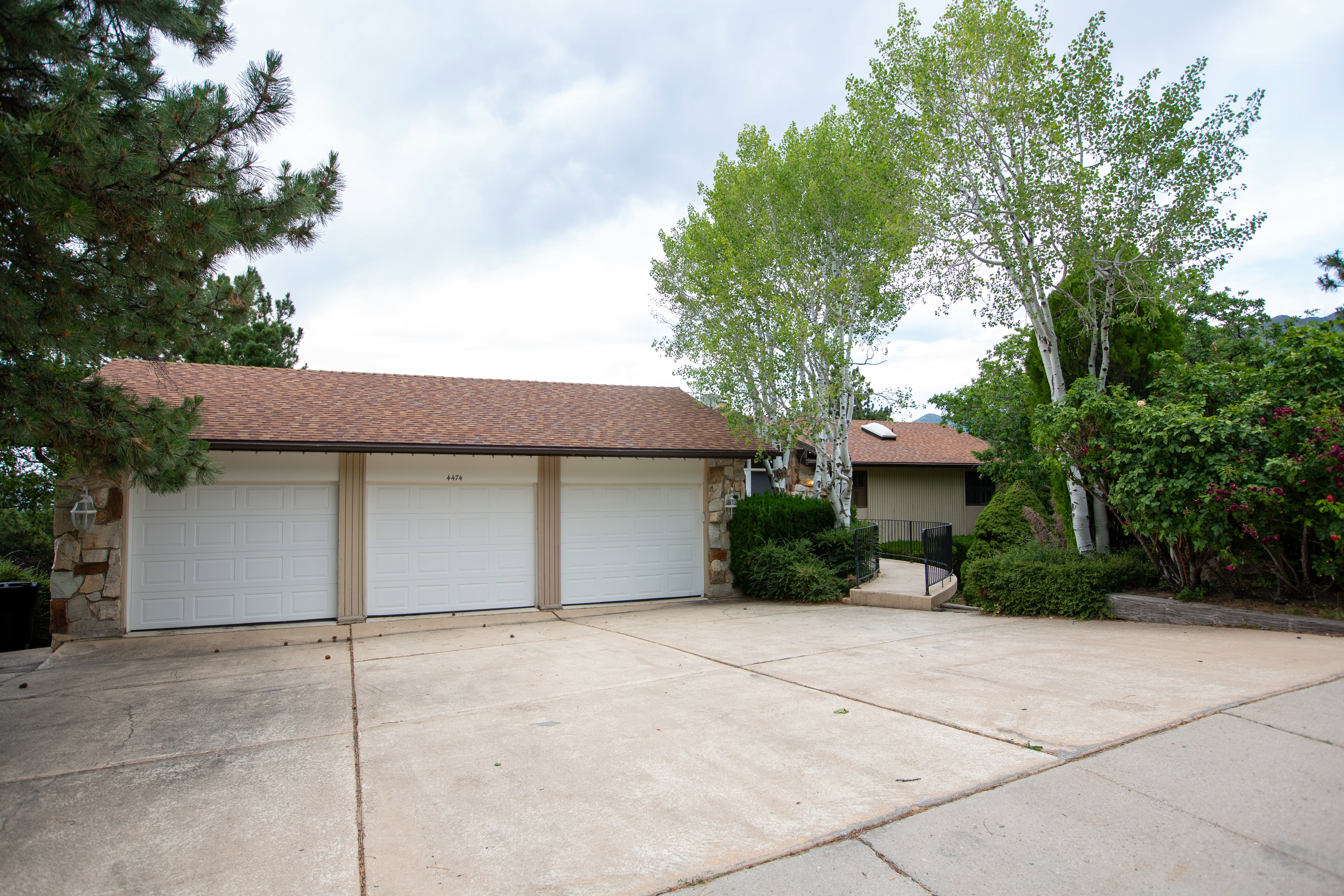 Three-car garage with white panel doors and a stone facade