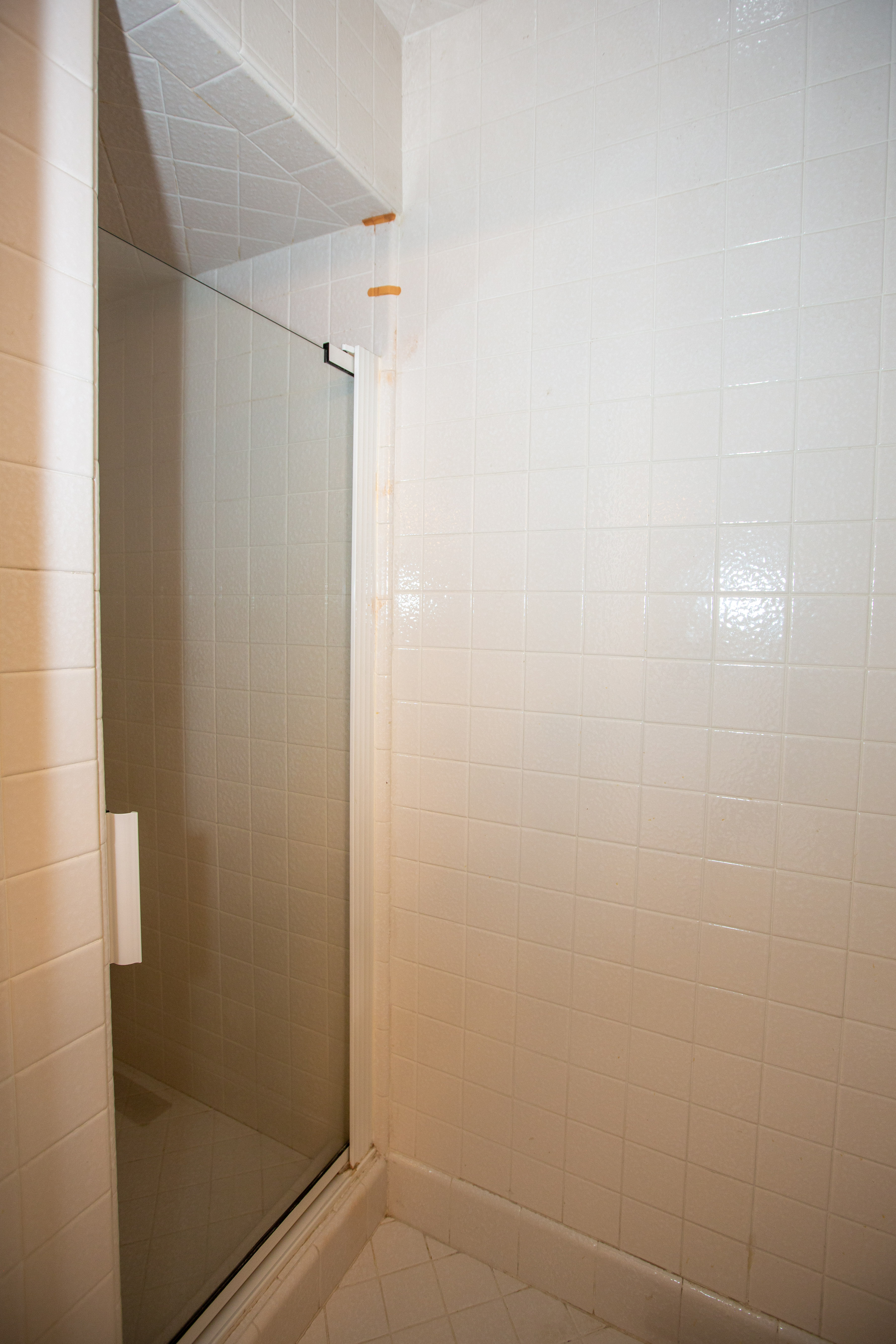 Master shower enclosure featuring a framed glass door, white square tile walls, and a tiled shower pan