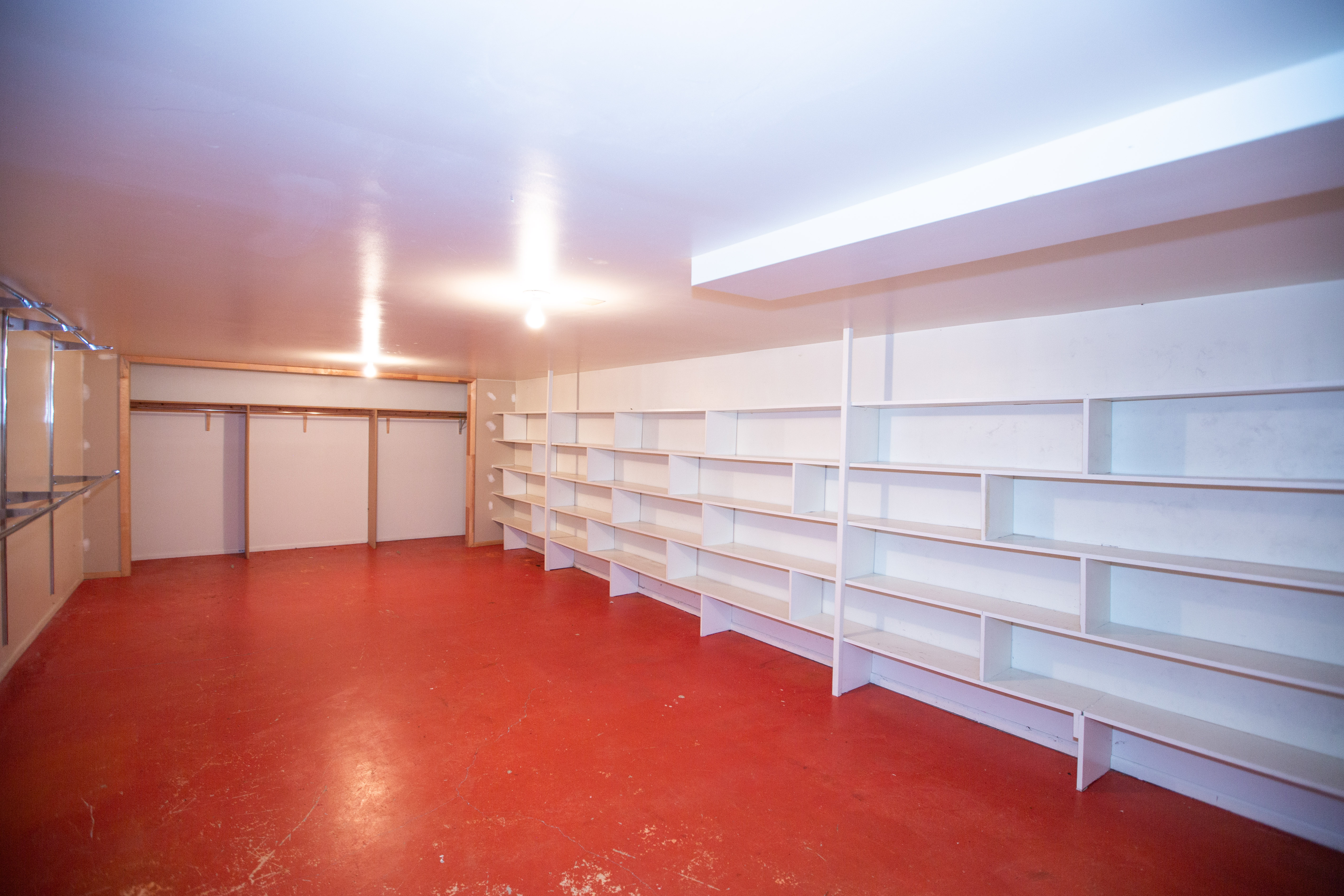 Spacious room featuring extensive built-in shelving, a bright red floor, and recessed lighting