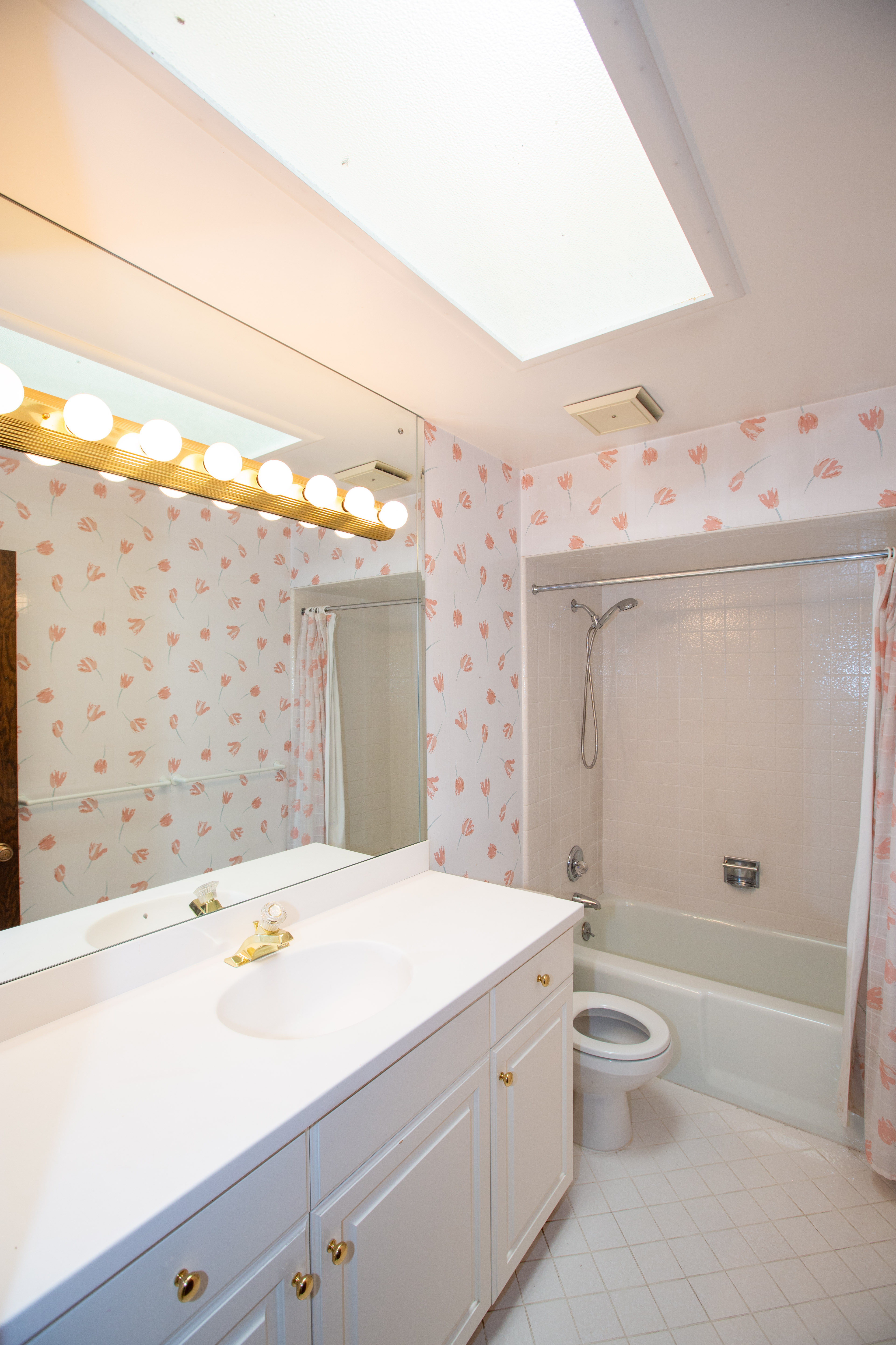 Bathroom with a white vanity featuring gold-tone hardware, a drop-in sink with a gold-tone faucet, and a large wall-mounted mirror