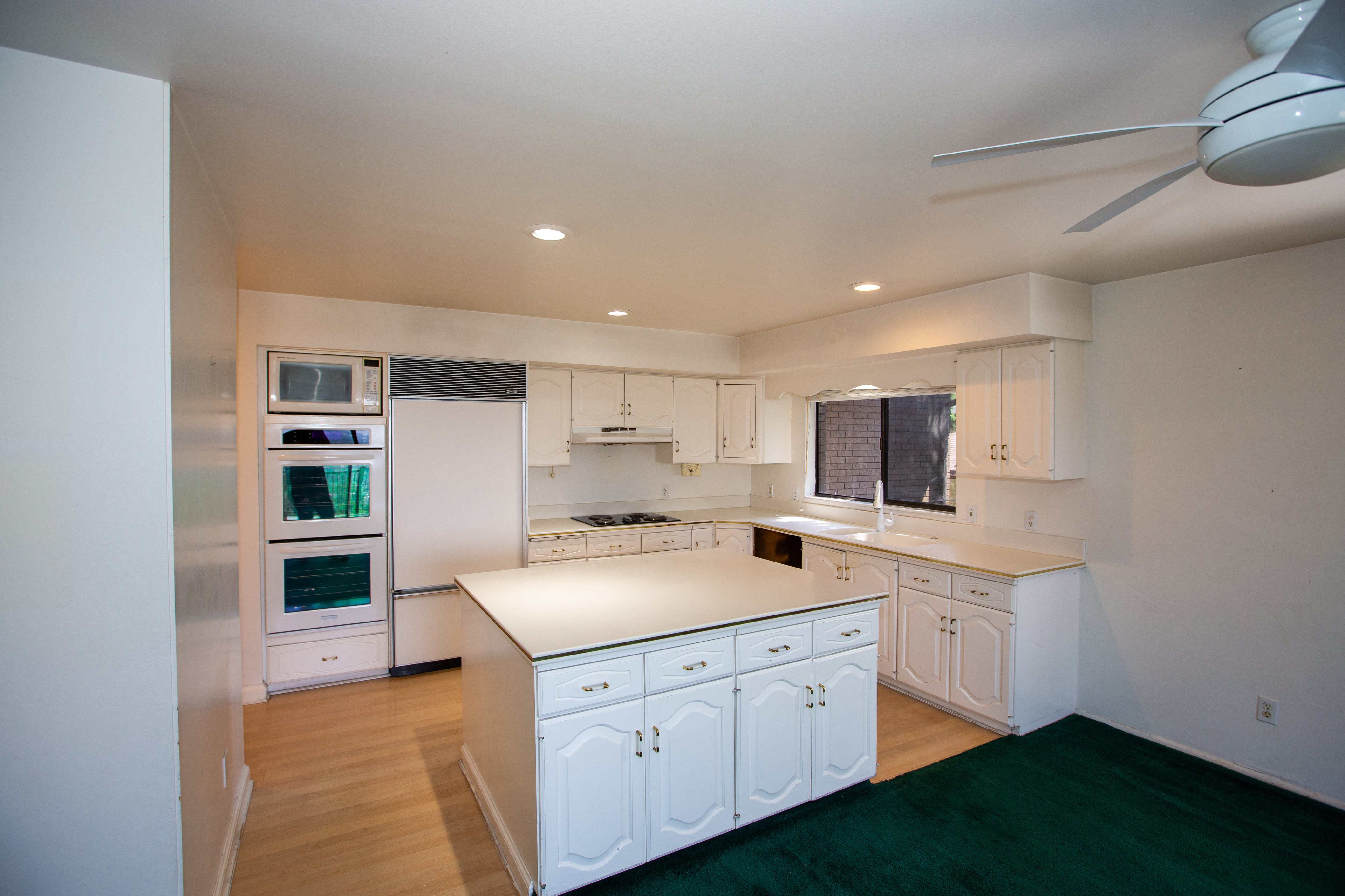 Kitchen featuring white cabinetry, a central island with storage, recessed lighting, and built-in appliances including a microwave and double ovens