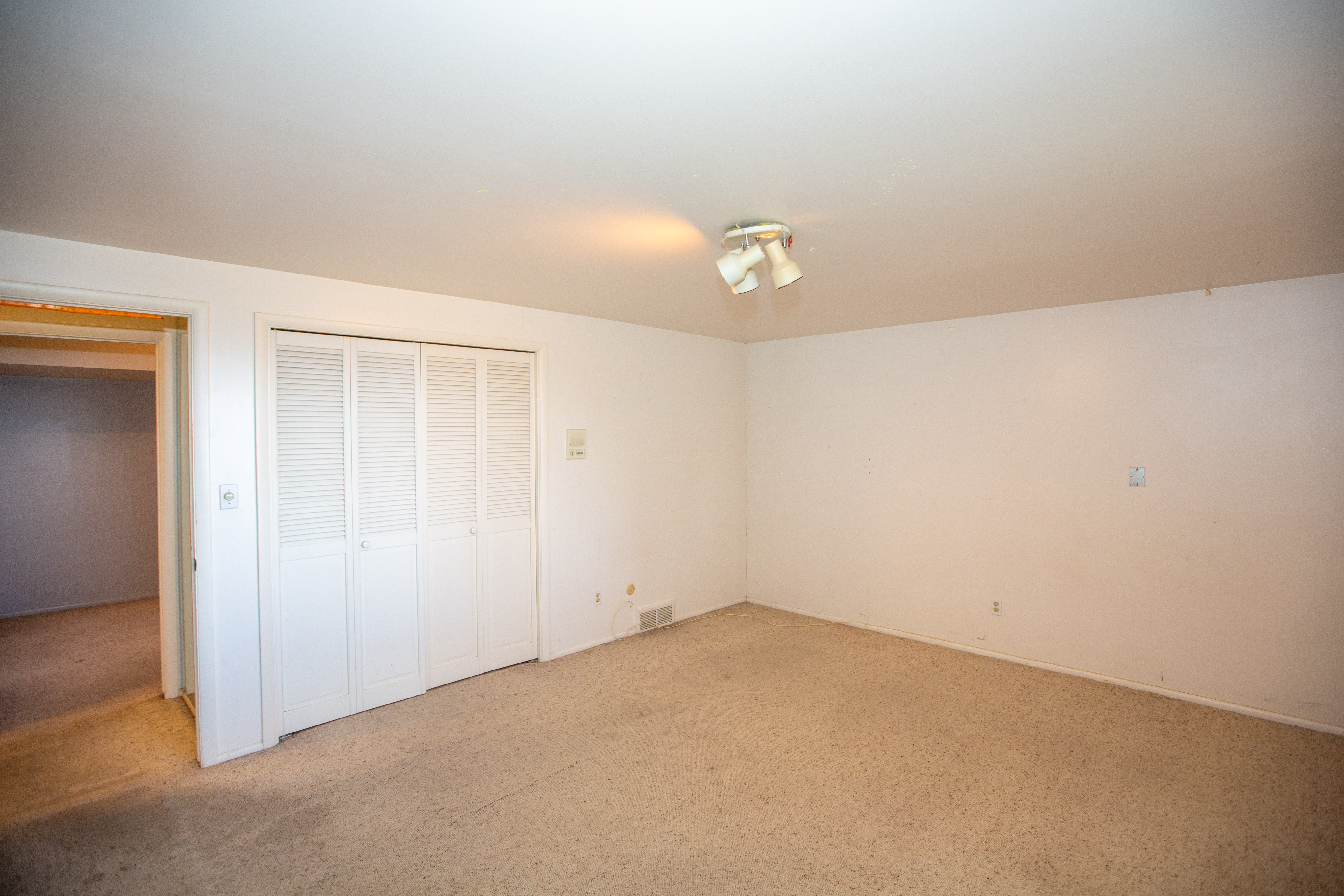 Spacious room with light-colored carpeting and white walls