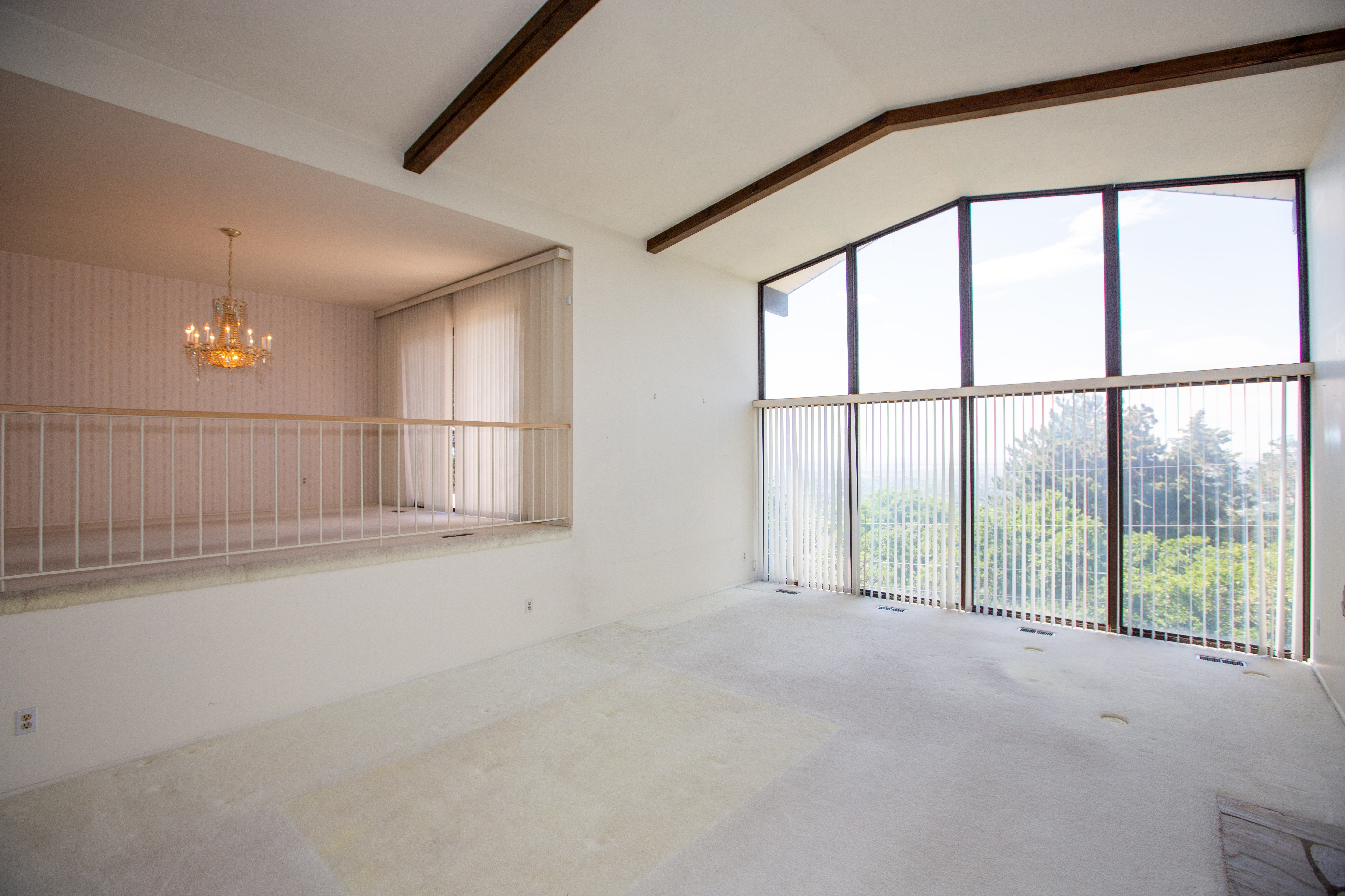 Spacious room featuring vaulted ceilings with exposed wood beams, a full wall of tall windows