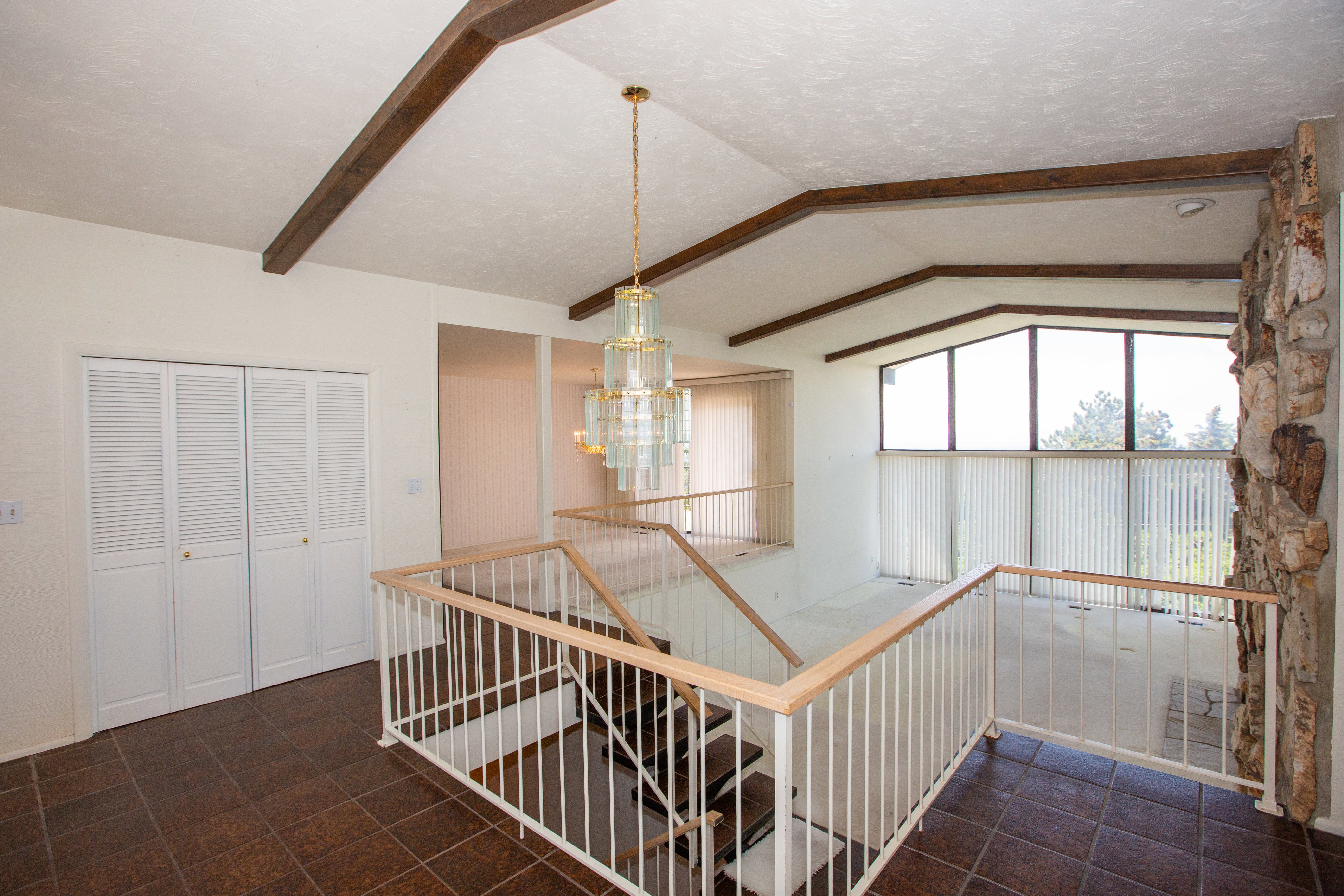 Entryway with tile flooring, a multi-tiered chandelier, and a prominent stone fireplace
