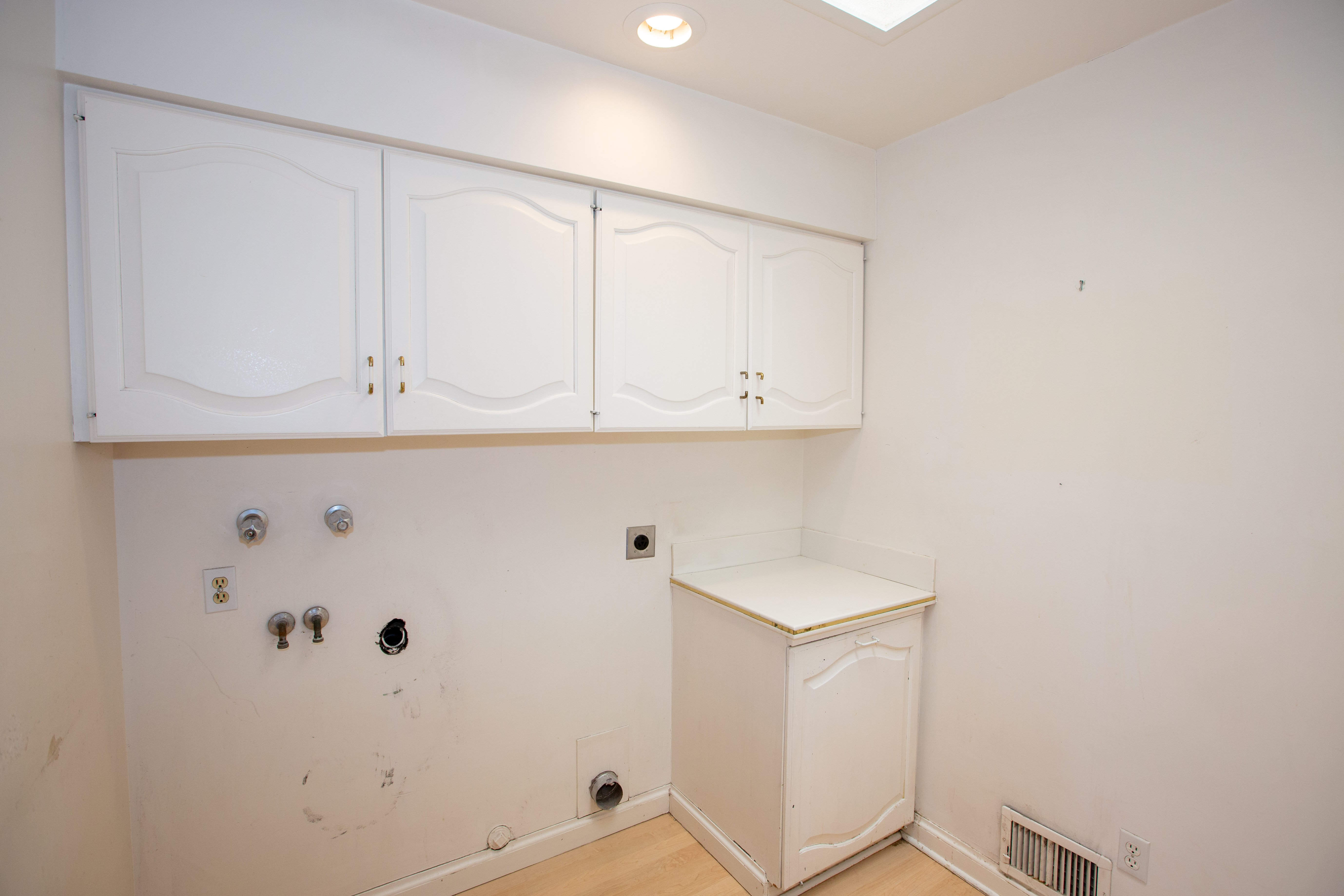 Laundry area featuring white cabinetry, a utility sink base cabinet with a countertop, recessed lighting, and a ceiling skylight