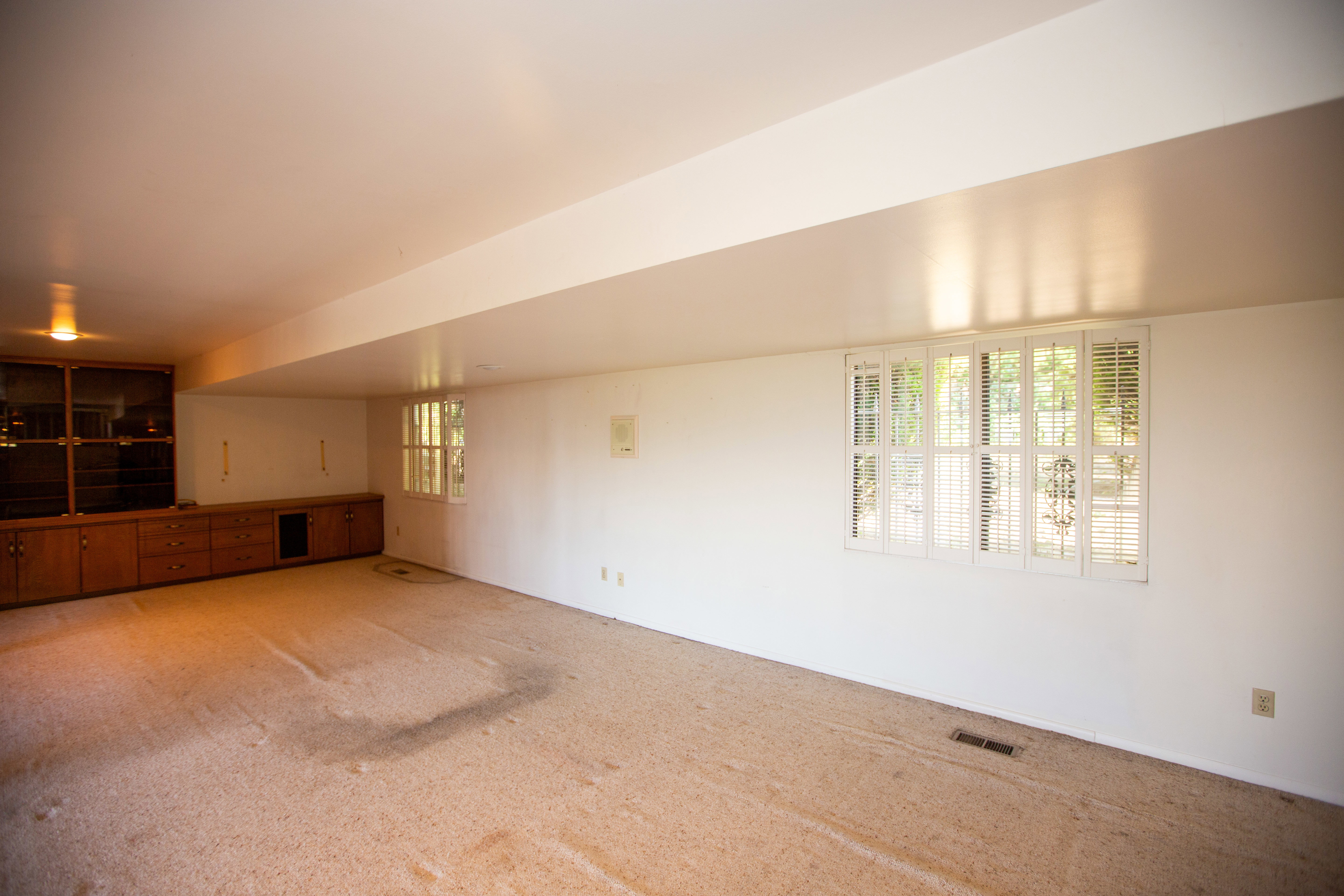 Spacious recreation room with light-colored carpeting and white walls
