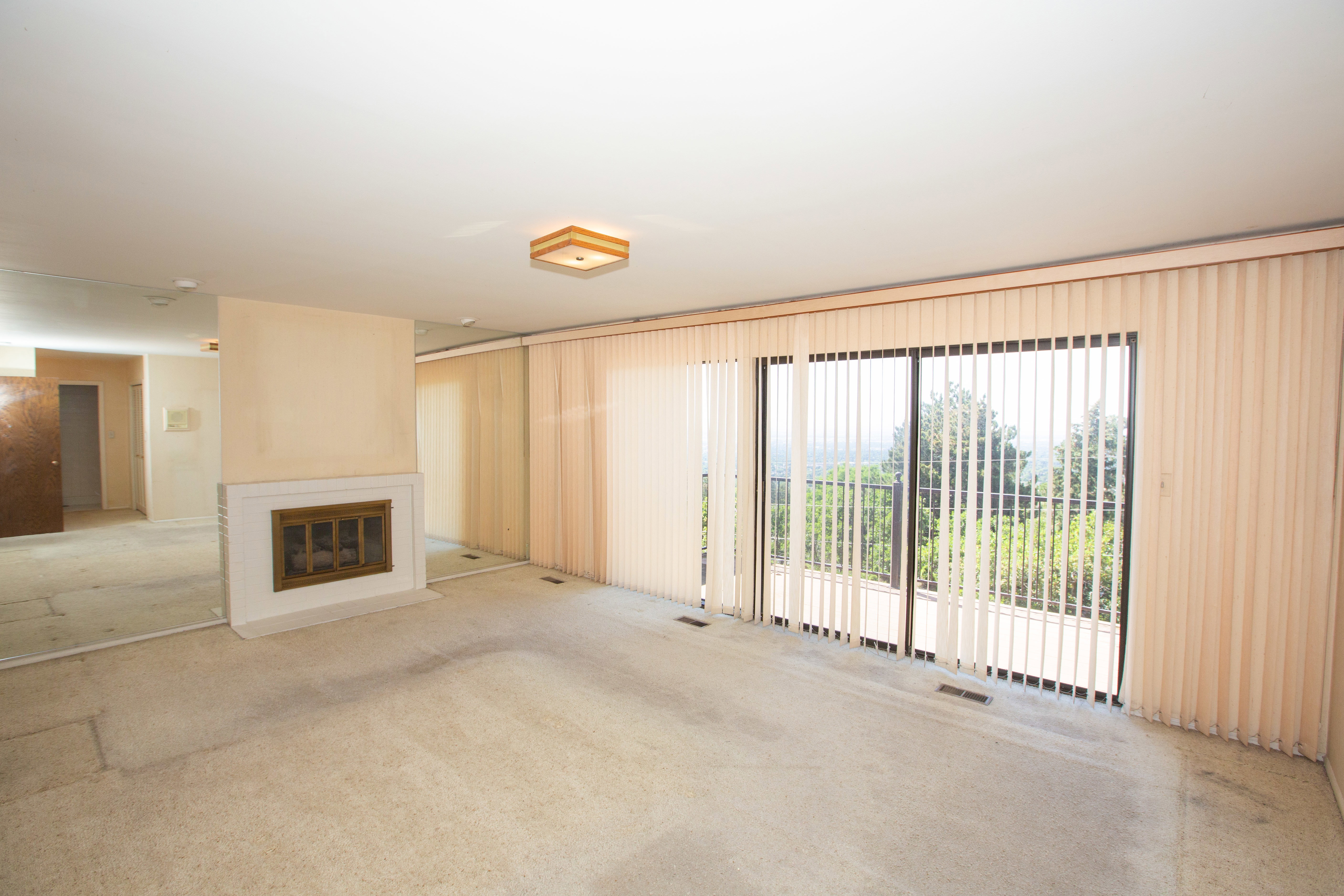 Spacious master suite featuring a fireplace with a white mantel, mirrored wall accents, and large sliding glass doors