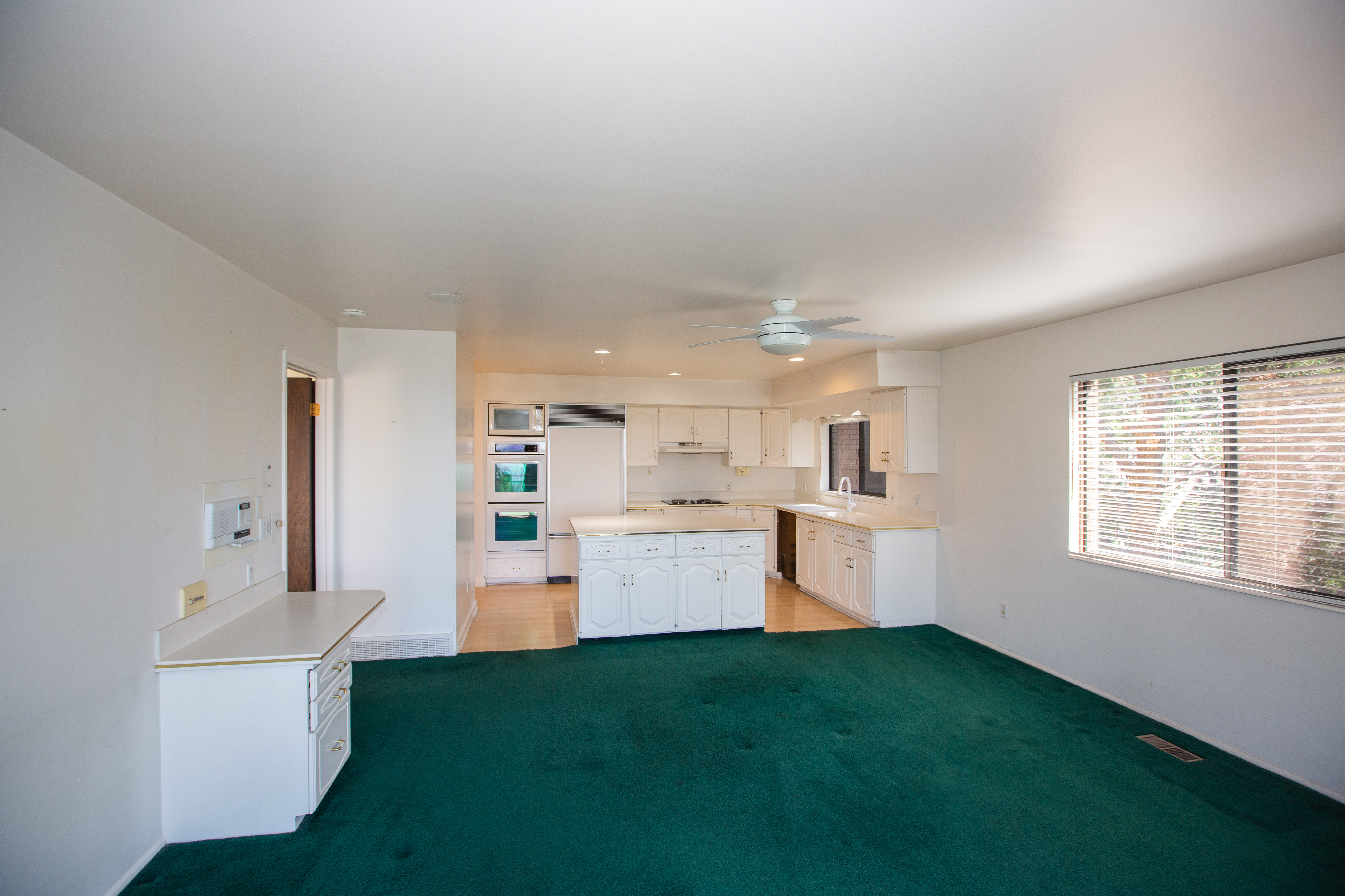 Family room and kitchen featuring white cabinetry, light-toned countertops, and integrated appliances