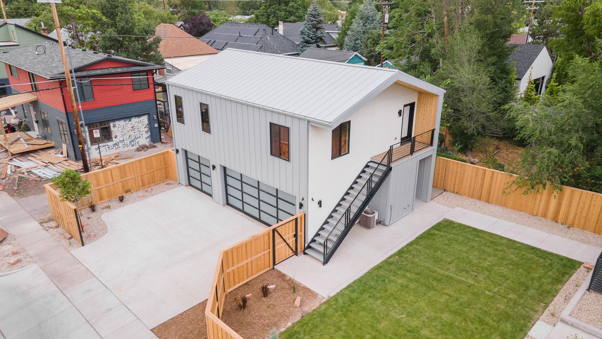Modern exterior featuring a white facade, metal roof, and dark trim windows