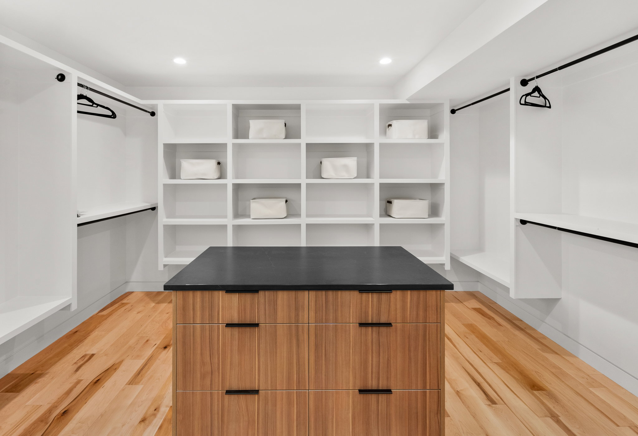 Spacious closet featuring an integrated wood-finish island with a dark countertop and drawer storage