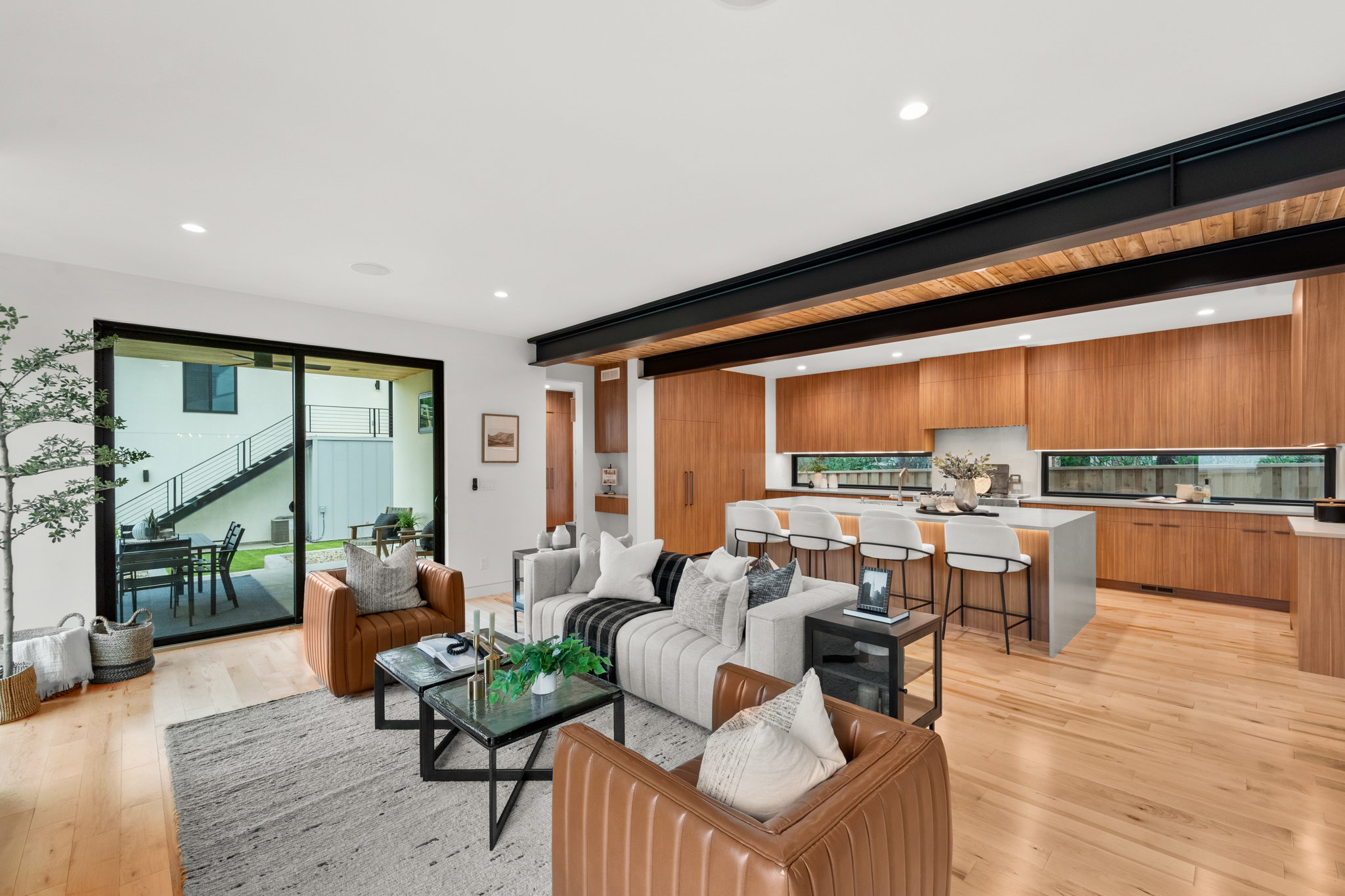 Open-concept living area featuring blonde wood-finish flooring, recessed lighting, and a structural beam