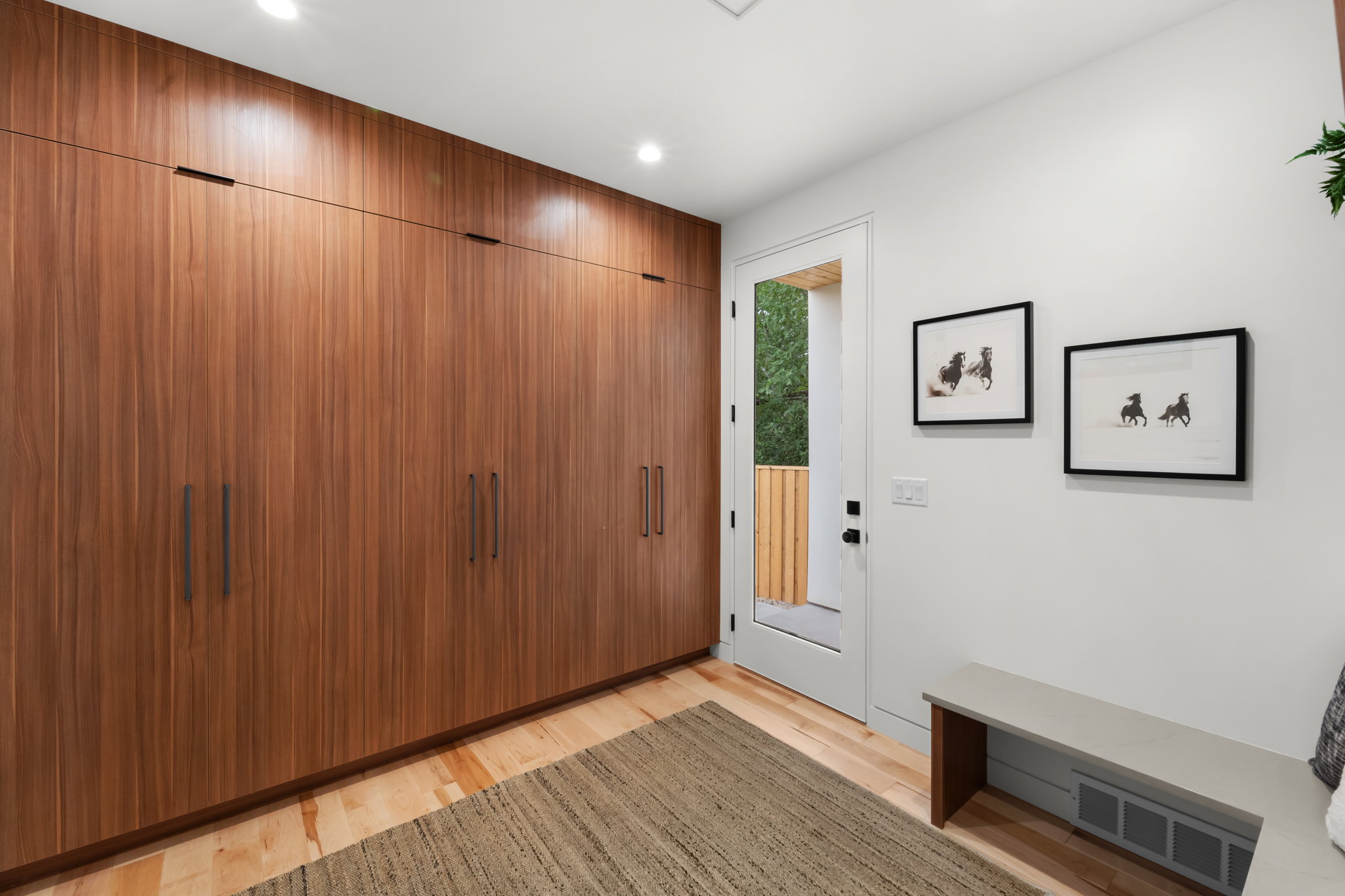 Integrated full-height wood-finish cabinetry featuring black hardware, recessed ceiling lighting, and light wood-finish flooring