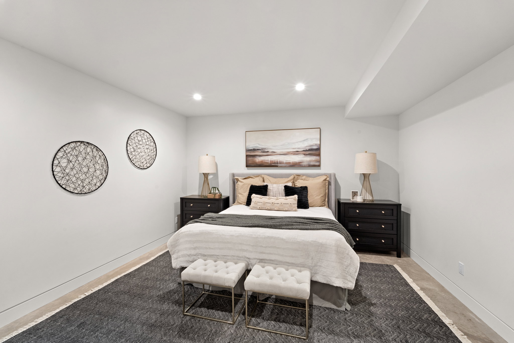Recessed lighting illuminates this room, featuring light-toned walls and contrasting dark baseboards