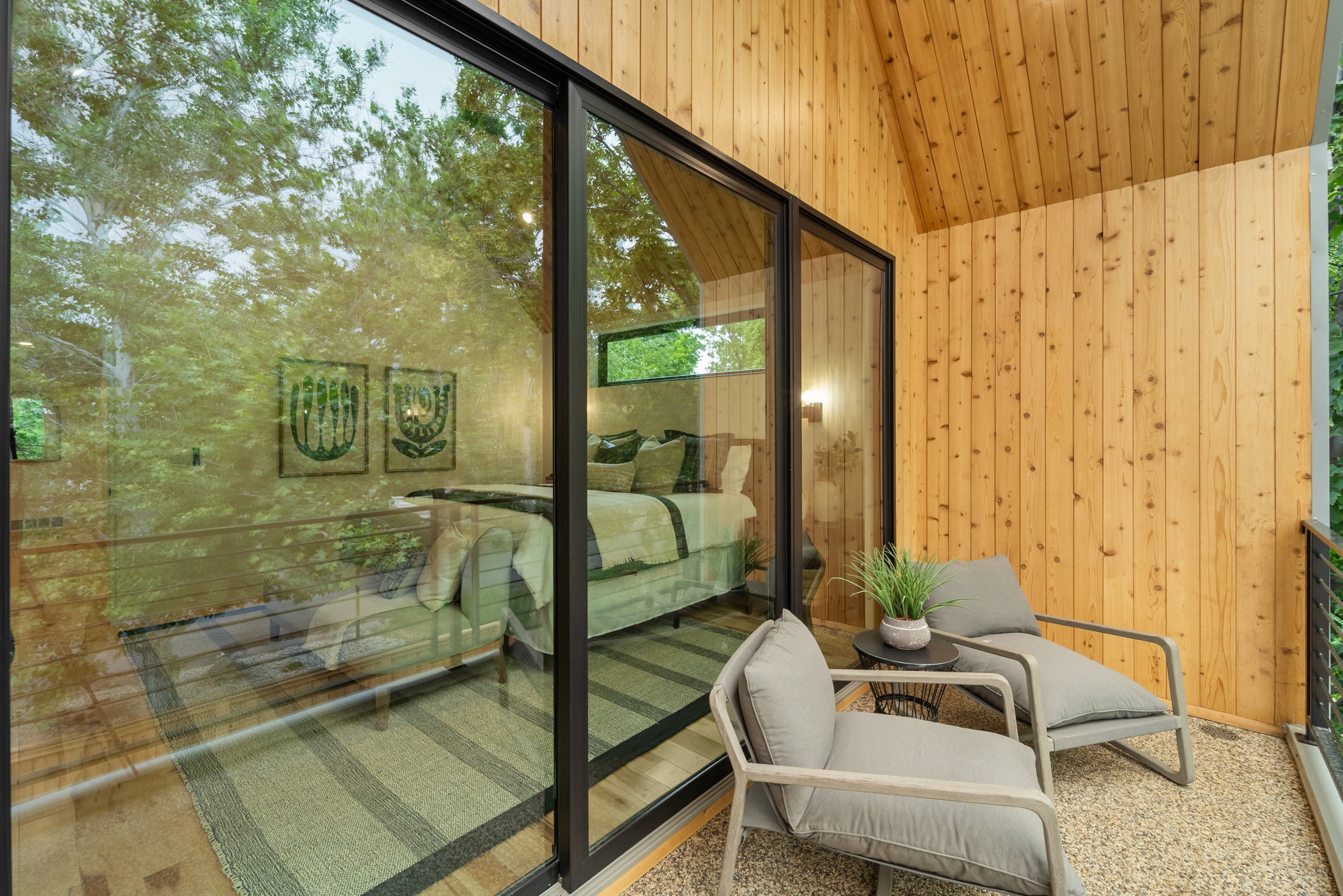 Private balcony featuring exposed aggregate flooring and a natural wood-paneled wall