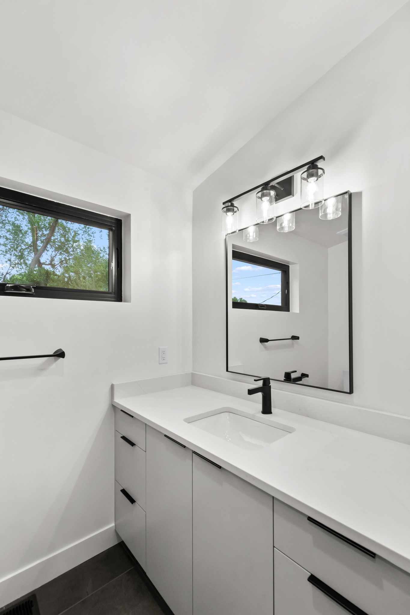 White countertop vanity with an integrated rectangular sink and matte black faucet