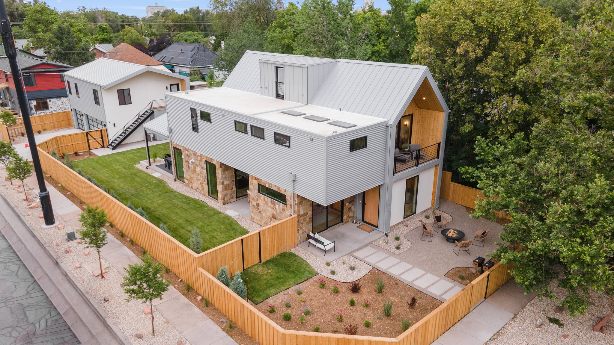 Contemporary residence featuring a light gray exterior with stone accents and a metal roof