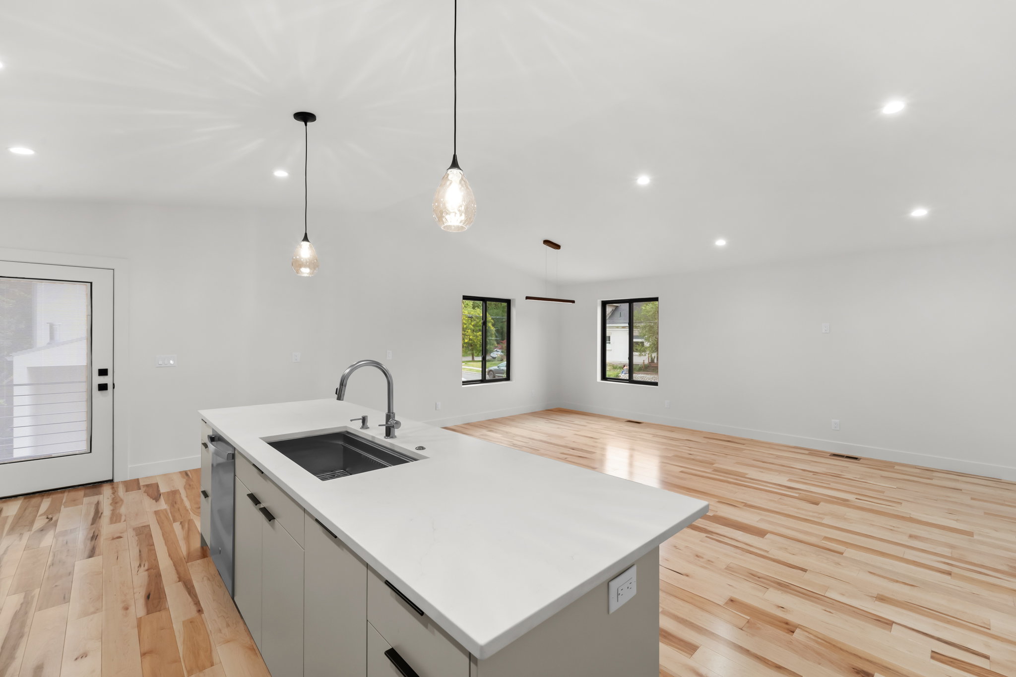 Kitchen island with an undermount sink, gooseneck faucet, and light gray cabinetry