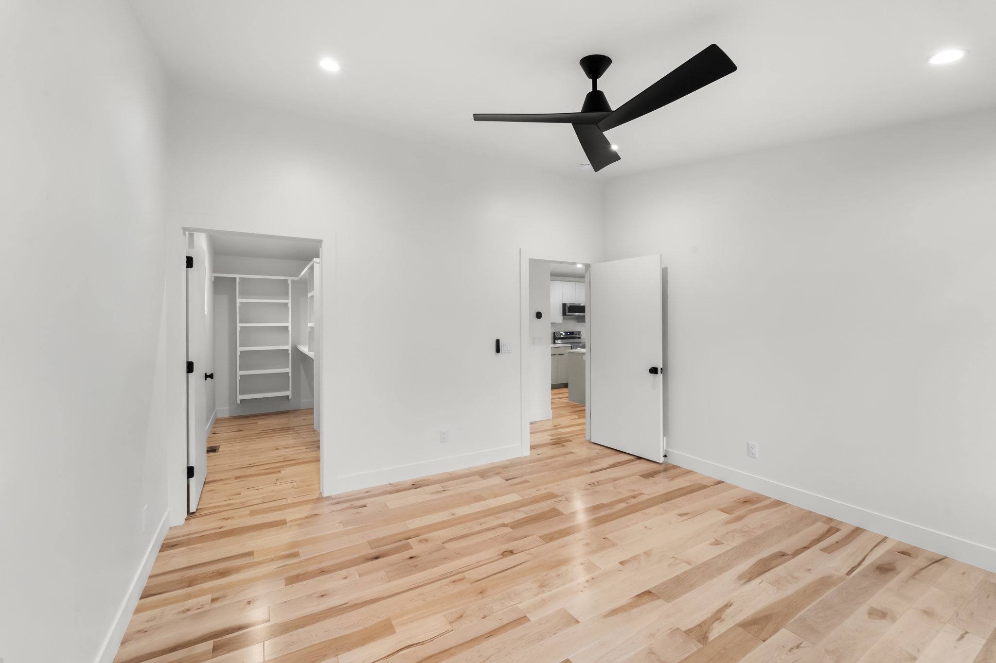 Open concept room with light wood-finish flooring, recessed lighting, and a modern black ceiling fan