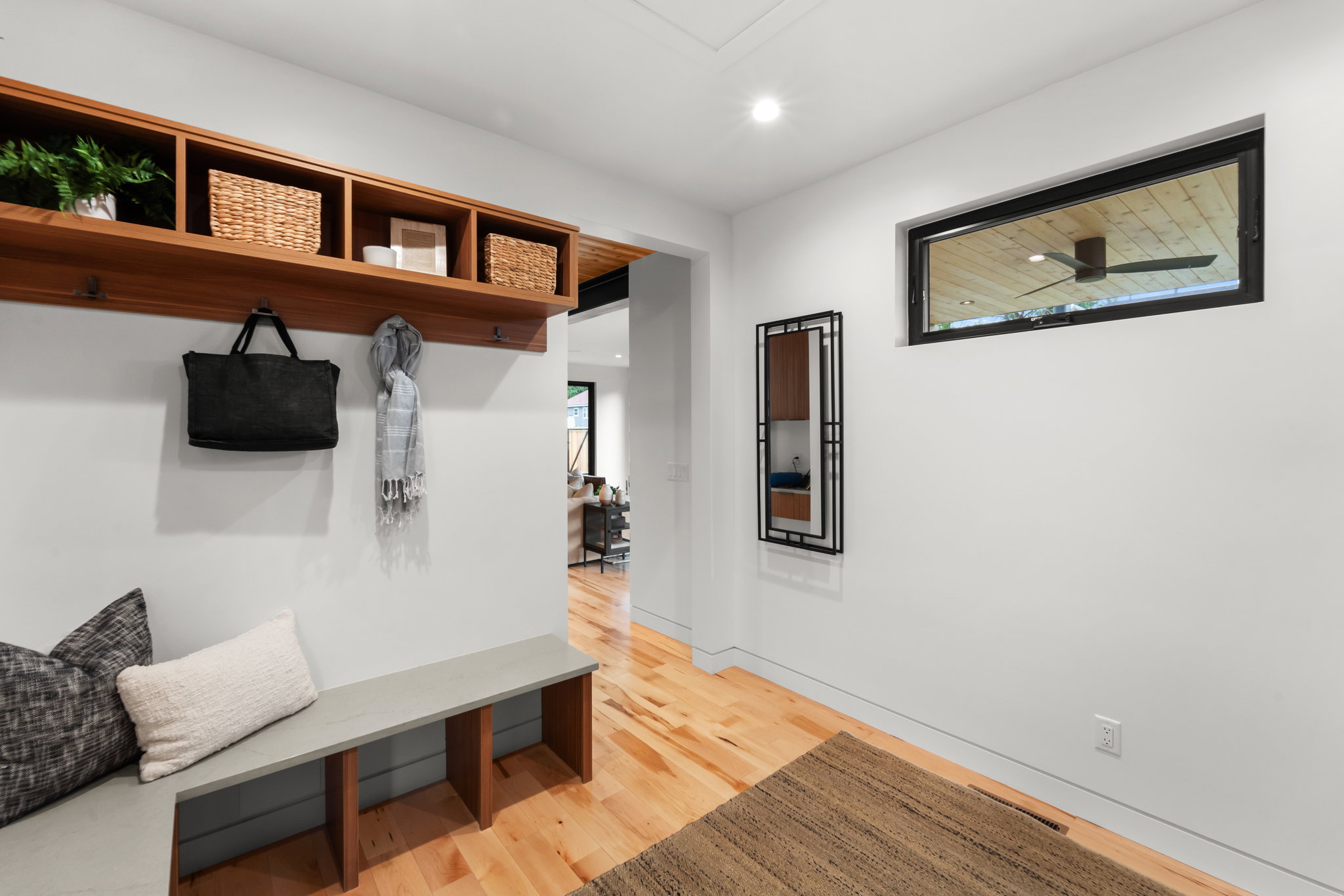 Entryway featuring built-in wood-finish shelving with hooks, a built-in bench, wood-finish flooring, recessed lighting, and a horizontal transom window