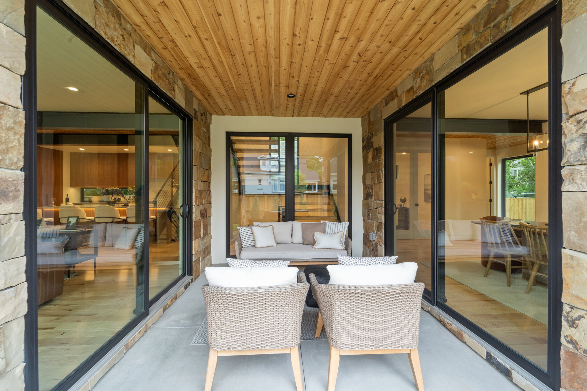 Covered outdoor living space featuring a cedar plank ceiling and stone accent walls