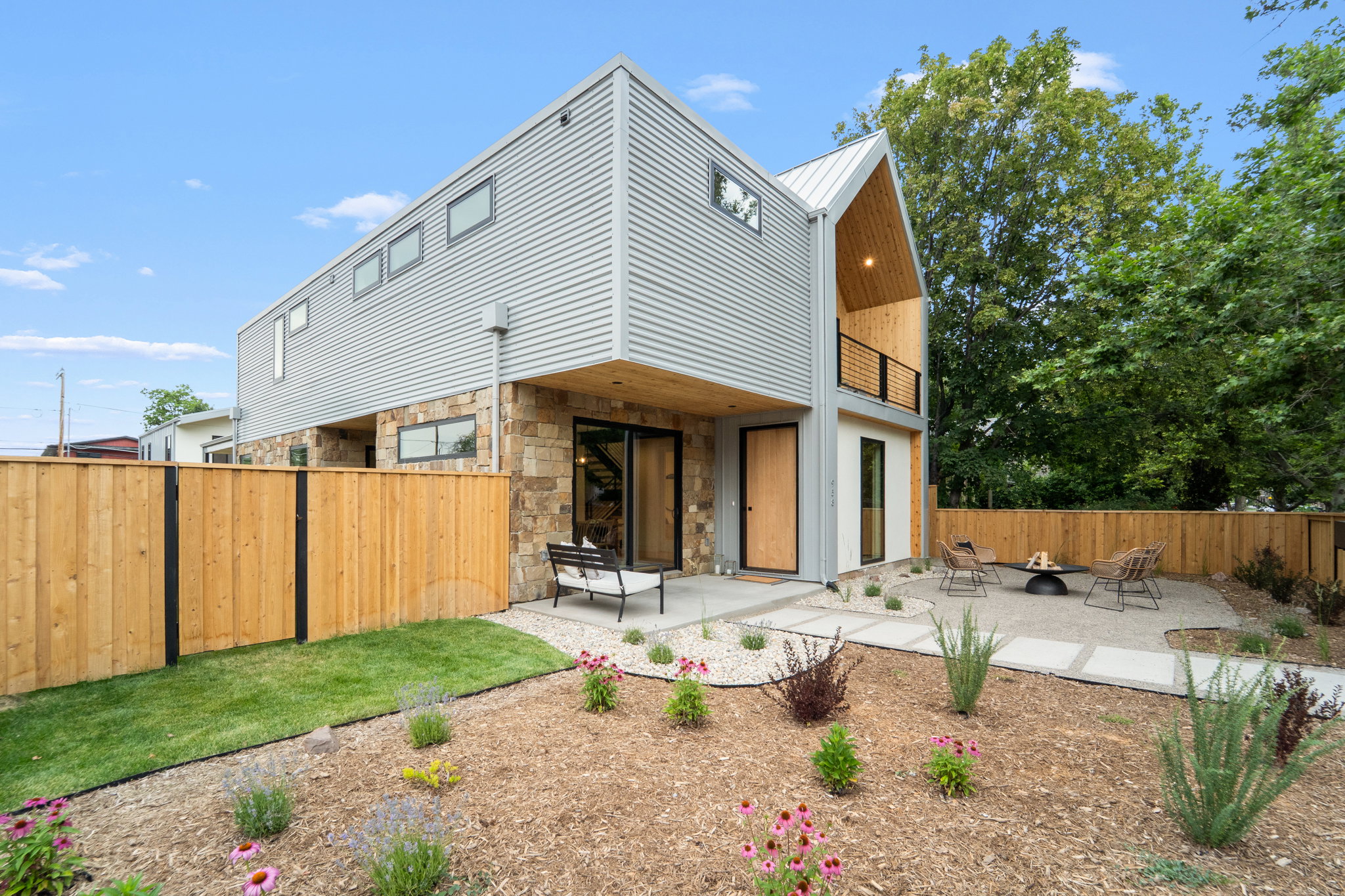 Contemporary exterior with corrugated metal siding, natural stone accents, and a distinctive gabled entry