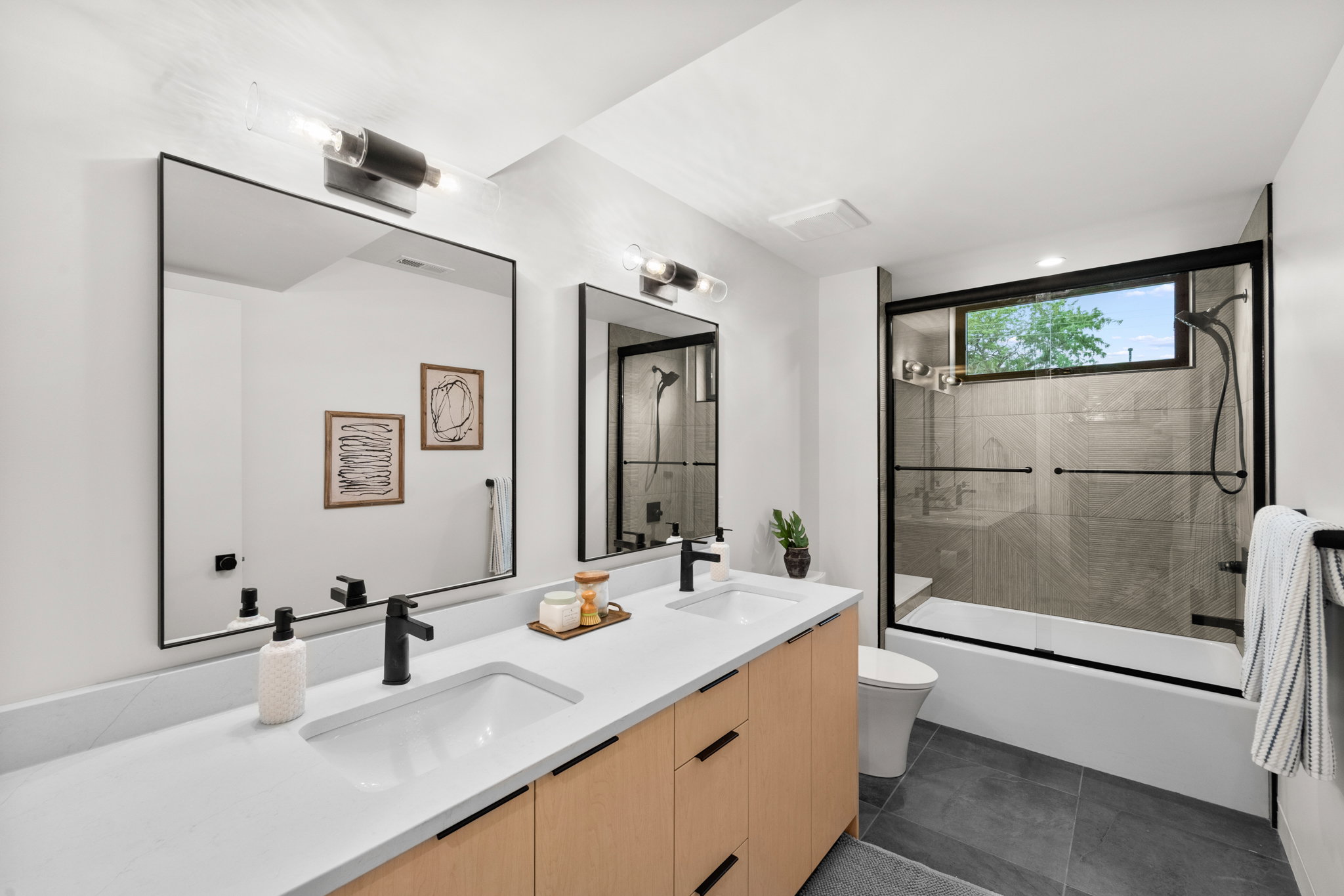 Contemporary bathroom featuring a double vanity with light wood-finish cabinetry and a white countertop