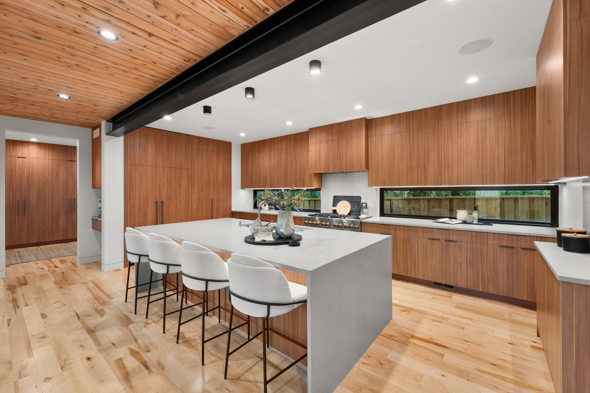Spacious kitchen featuring a large central island with seating, extensive wood-finish cabinetry, light wood flooring, and a natural wood plank ceiling