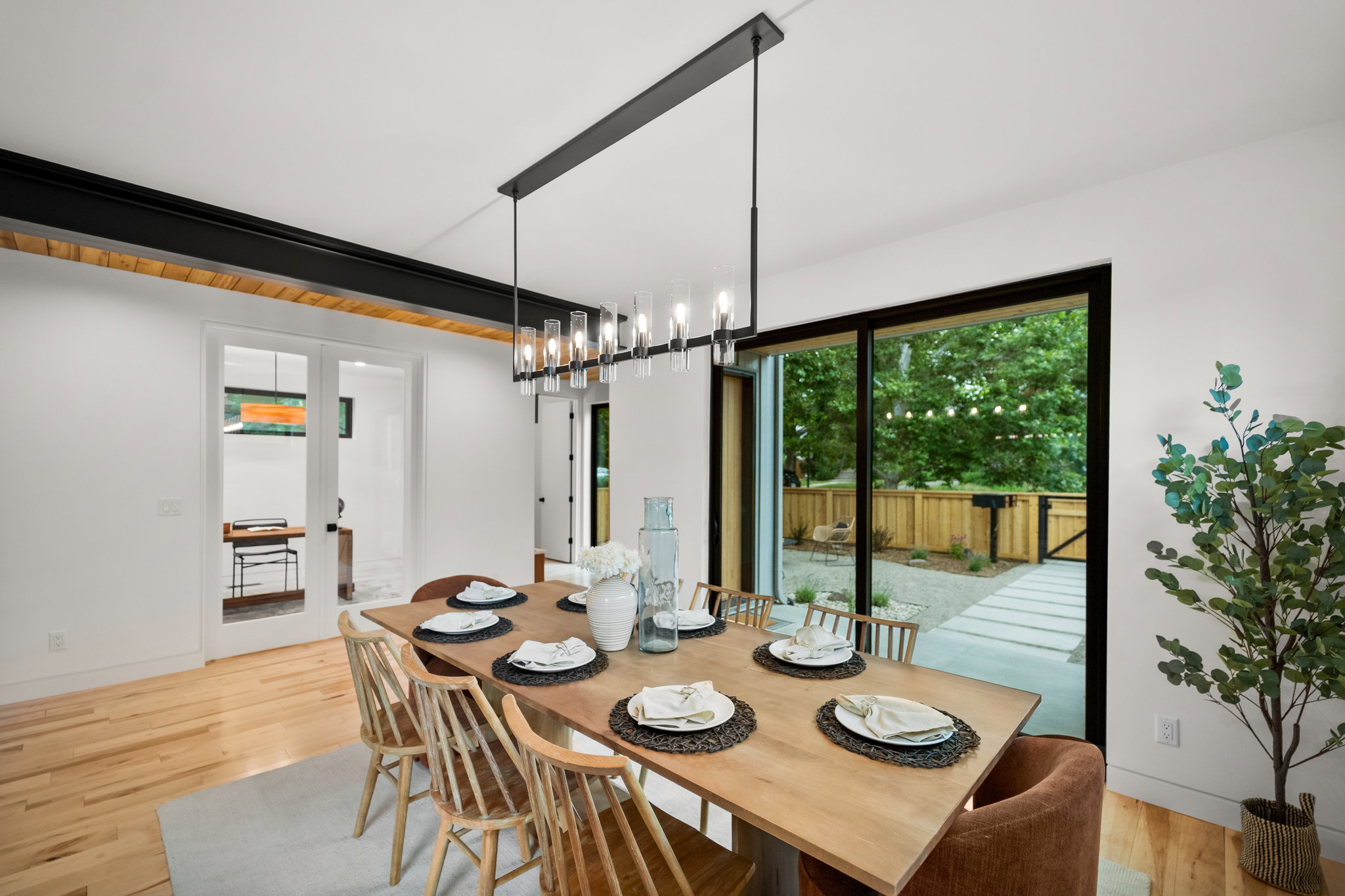 Dining area with wood-finish flooring, a modern linear chandelier, and white walls