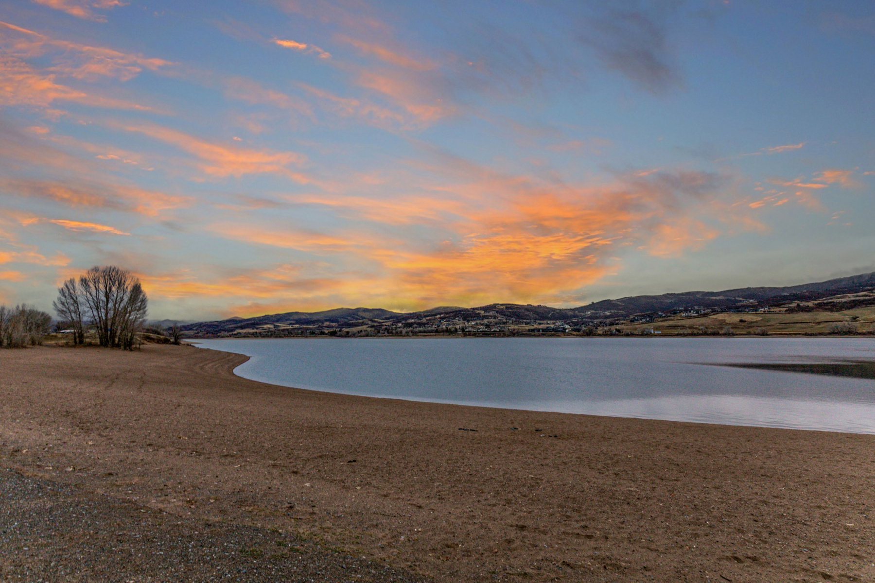 Expansive lakefront property featuring a sandy shoreline and distant hills