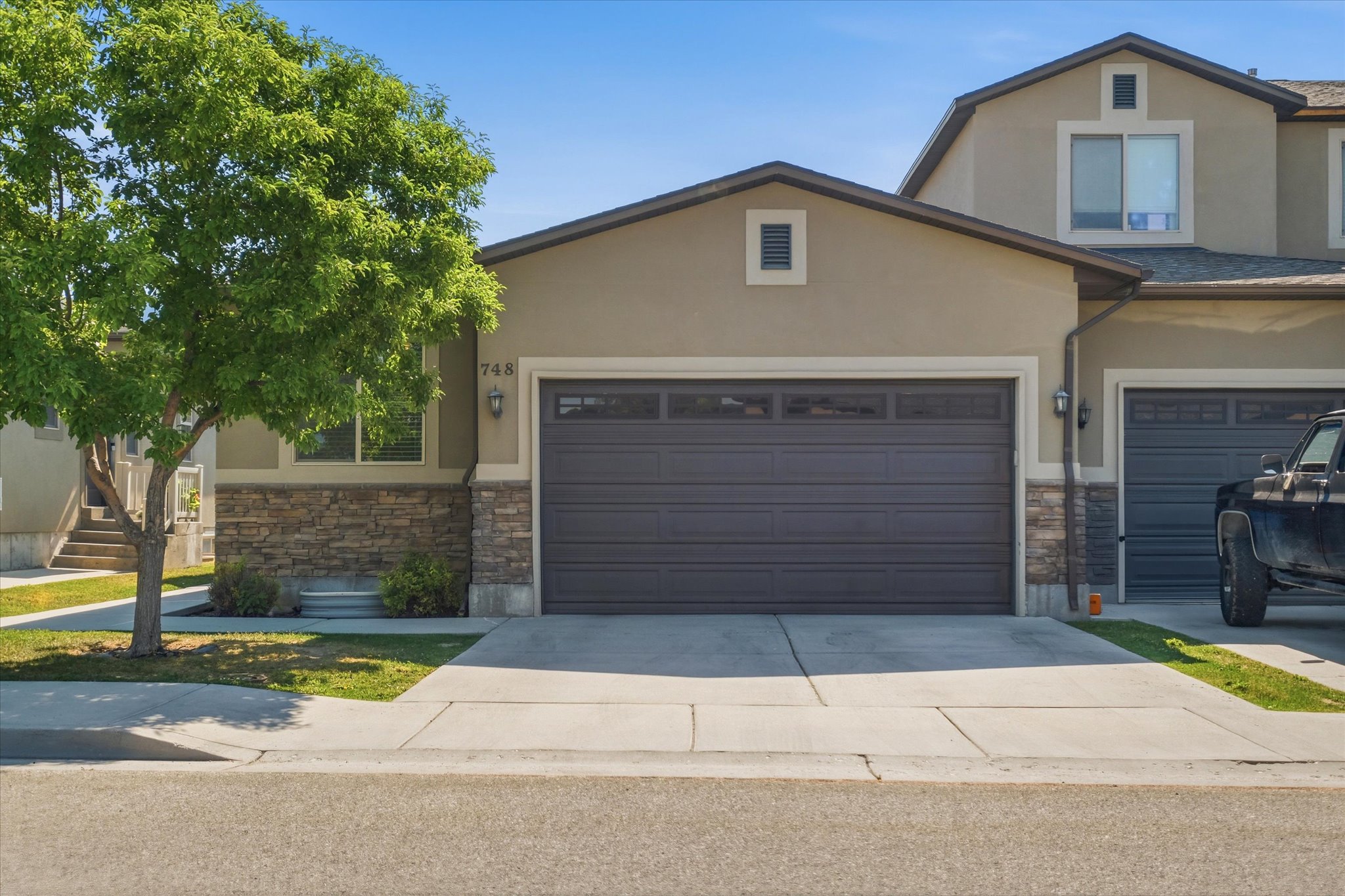 Stucco exterior with stone veneer accents and a two-car garage featuring transom windows