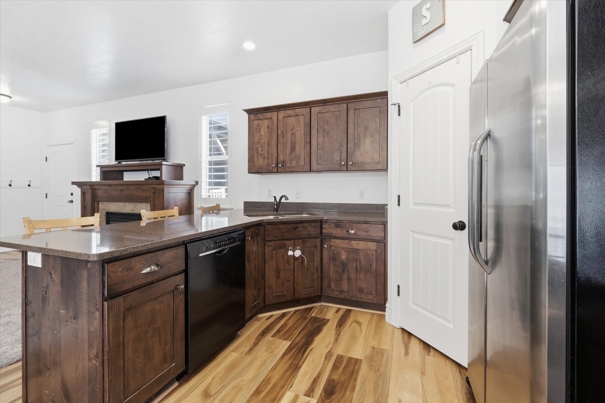 Kitchen featuring wood-finish flooring, dark wood cabinetry, and a black dishwasher