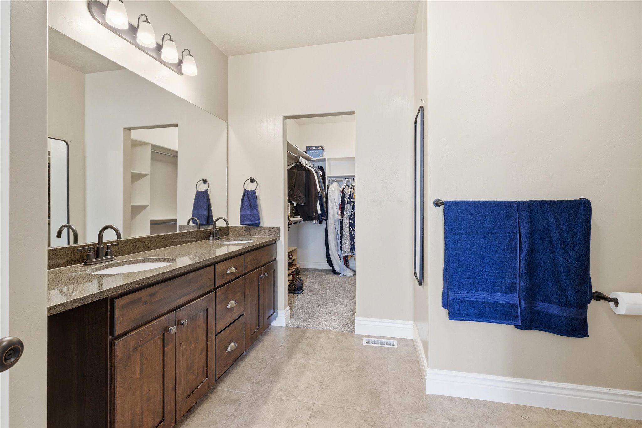 Double vanity with dark wood cabinetry, granite countertop, and dual sinks