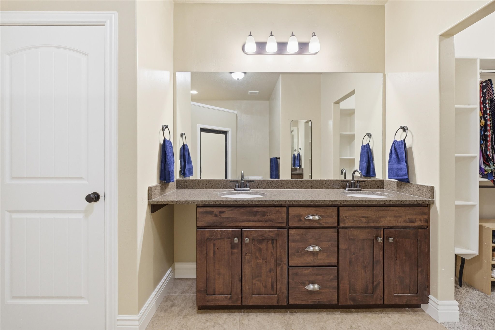Double vanity featuring a stone-finish countertop, dual sinks with dark-finish faucets, and a large mirror