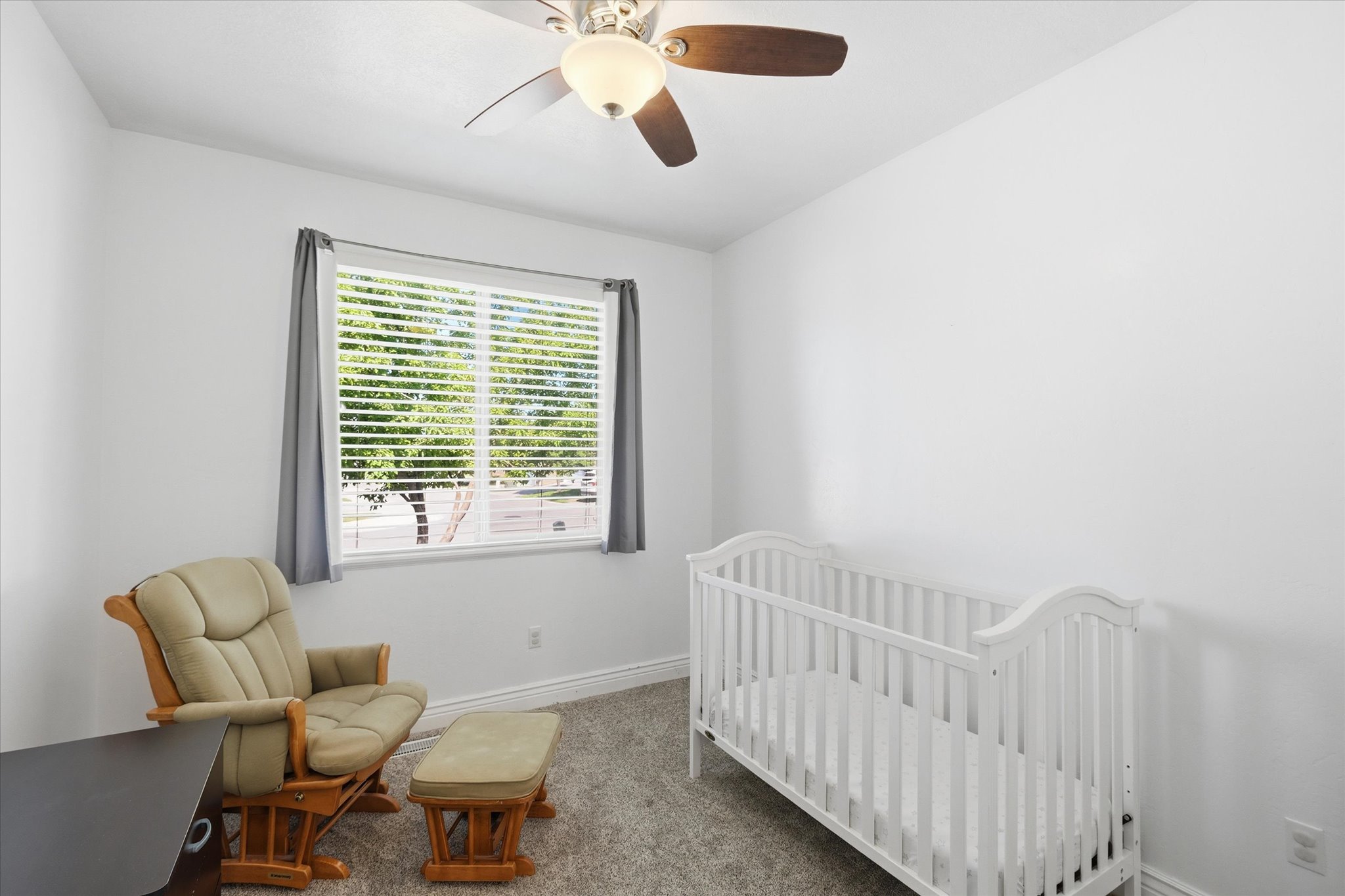 Carpeted interior space featuring a ceiling fan with integrated lighting, a window with horizontal blinds, and base molding