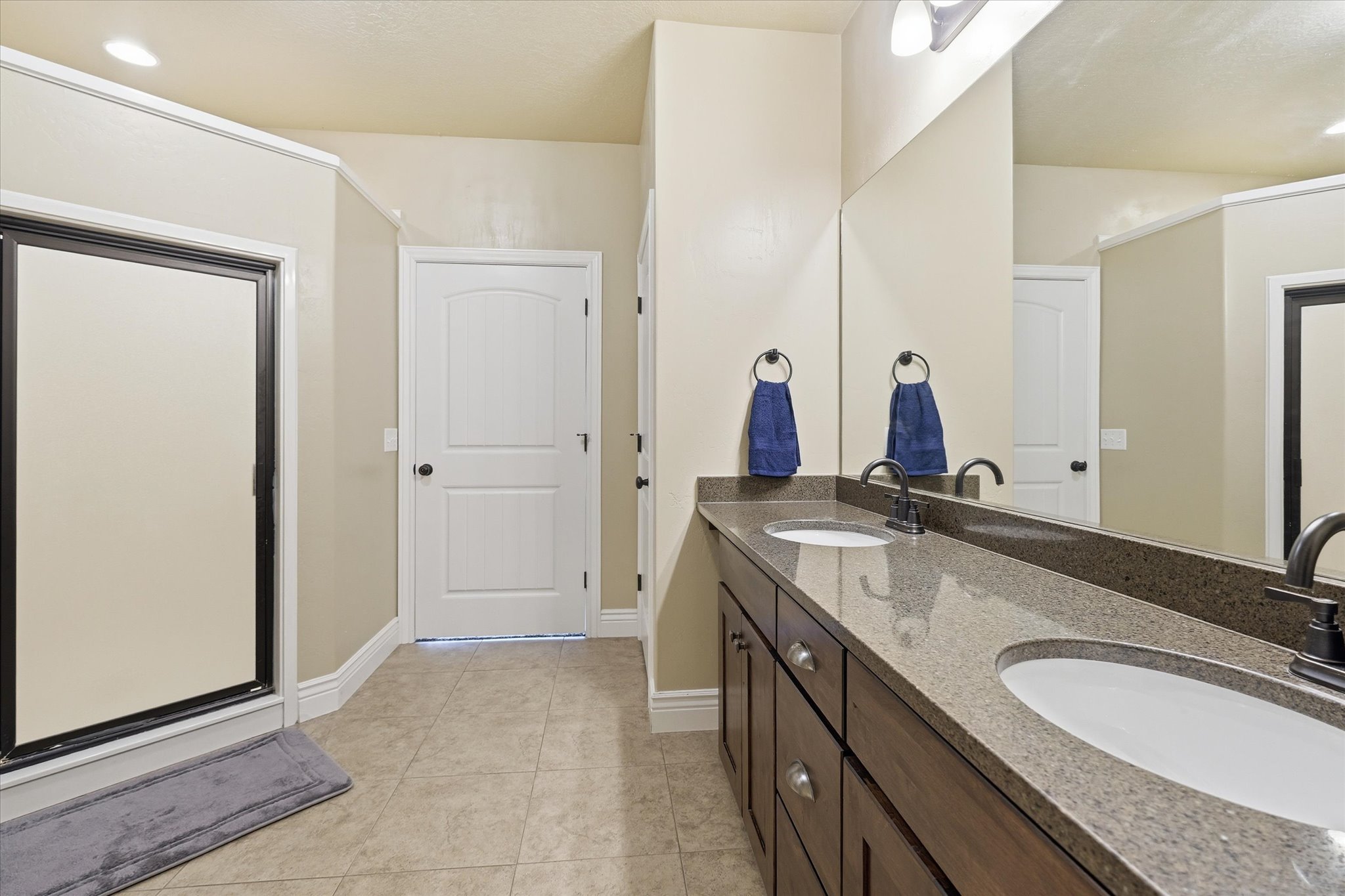 Dual vanity with a stone-finish countertop, dark wood-finish cabinetry, and matte black fixtures