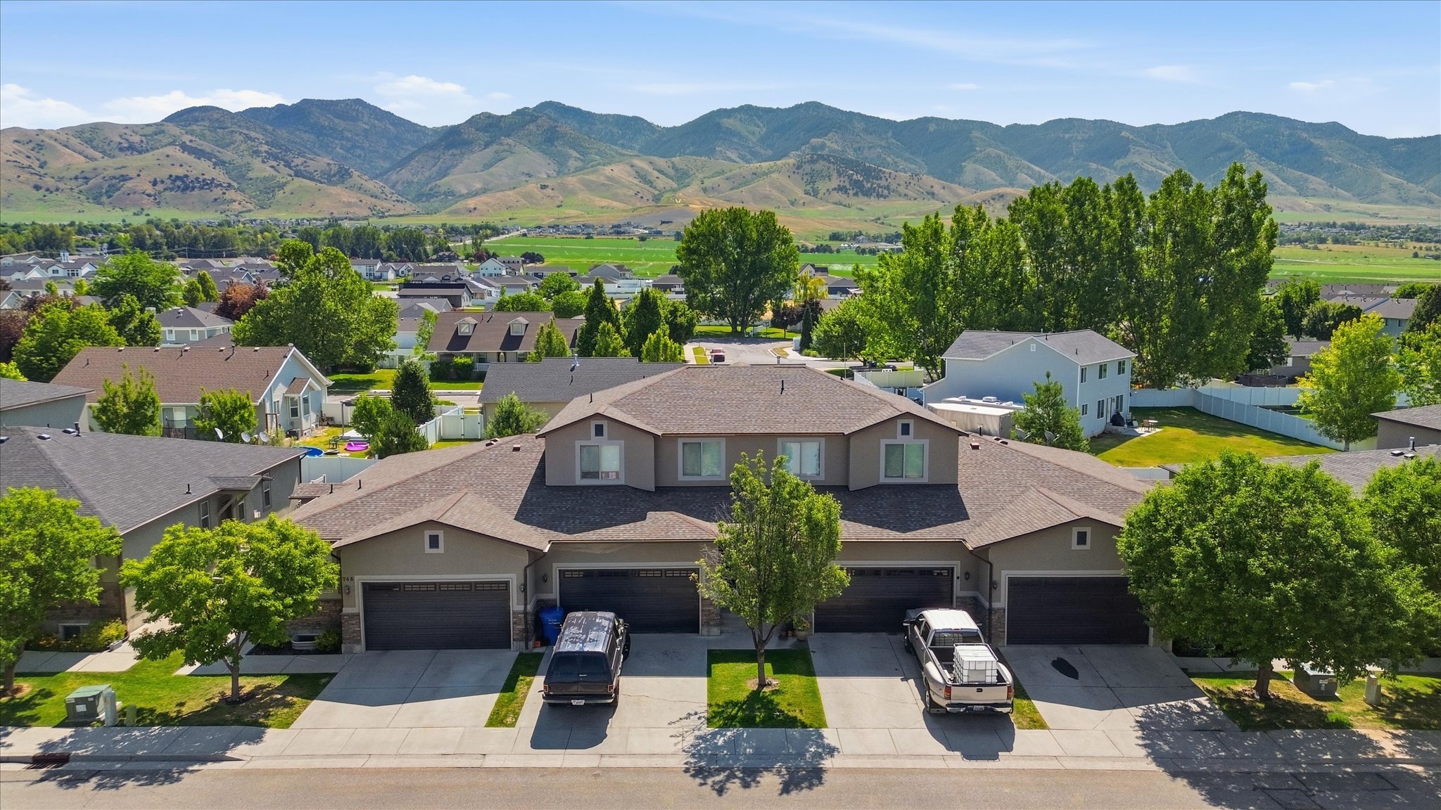 Modern multi-unit property featuring tan siding, dark garage doors, and individual driveways