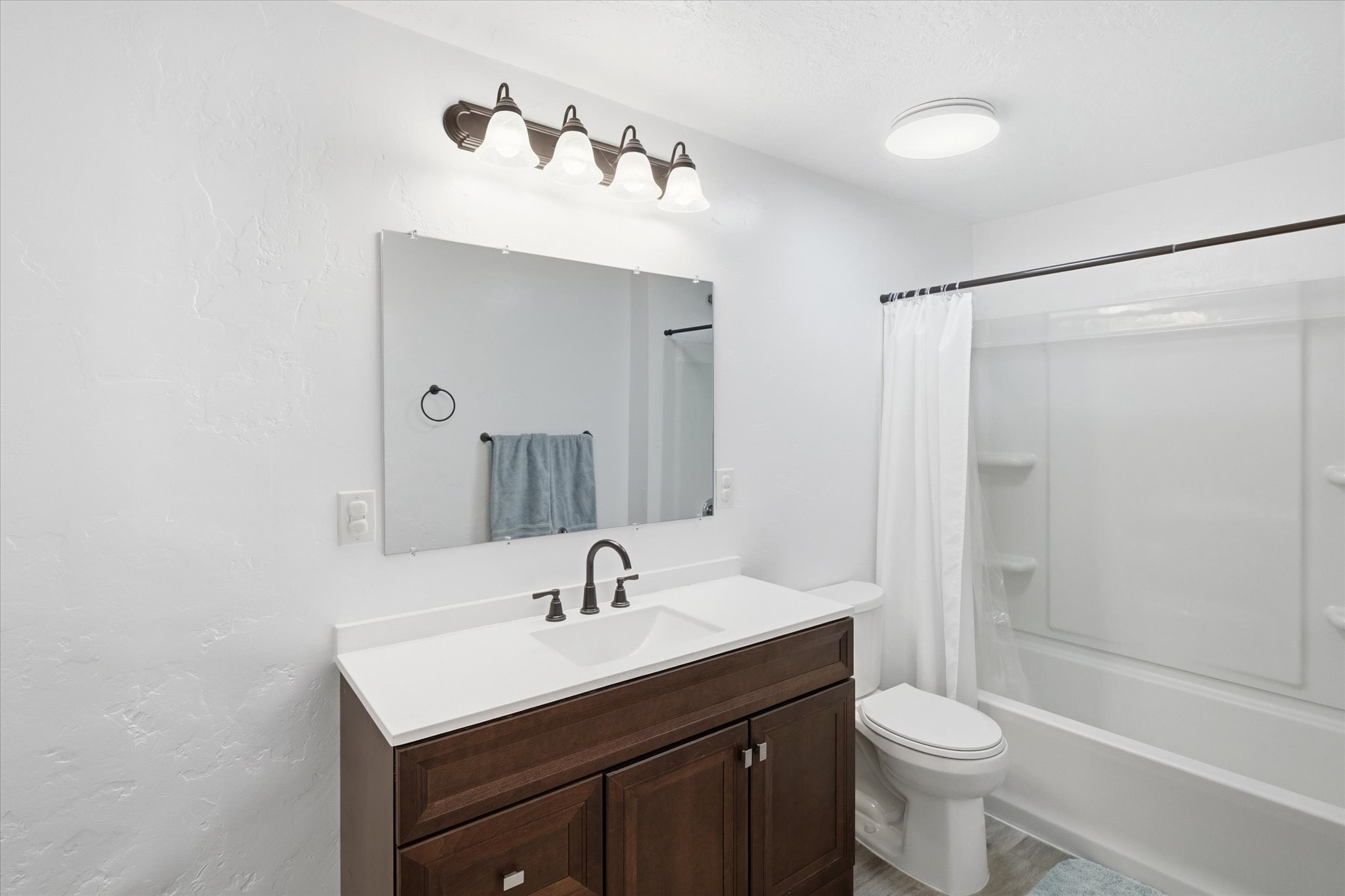 Bathroom featuring a brown wood-finish vanity with a white countertop and integrated sink, framed by a rectangular mirror