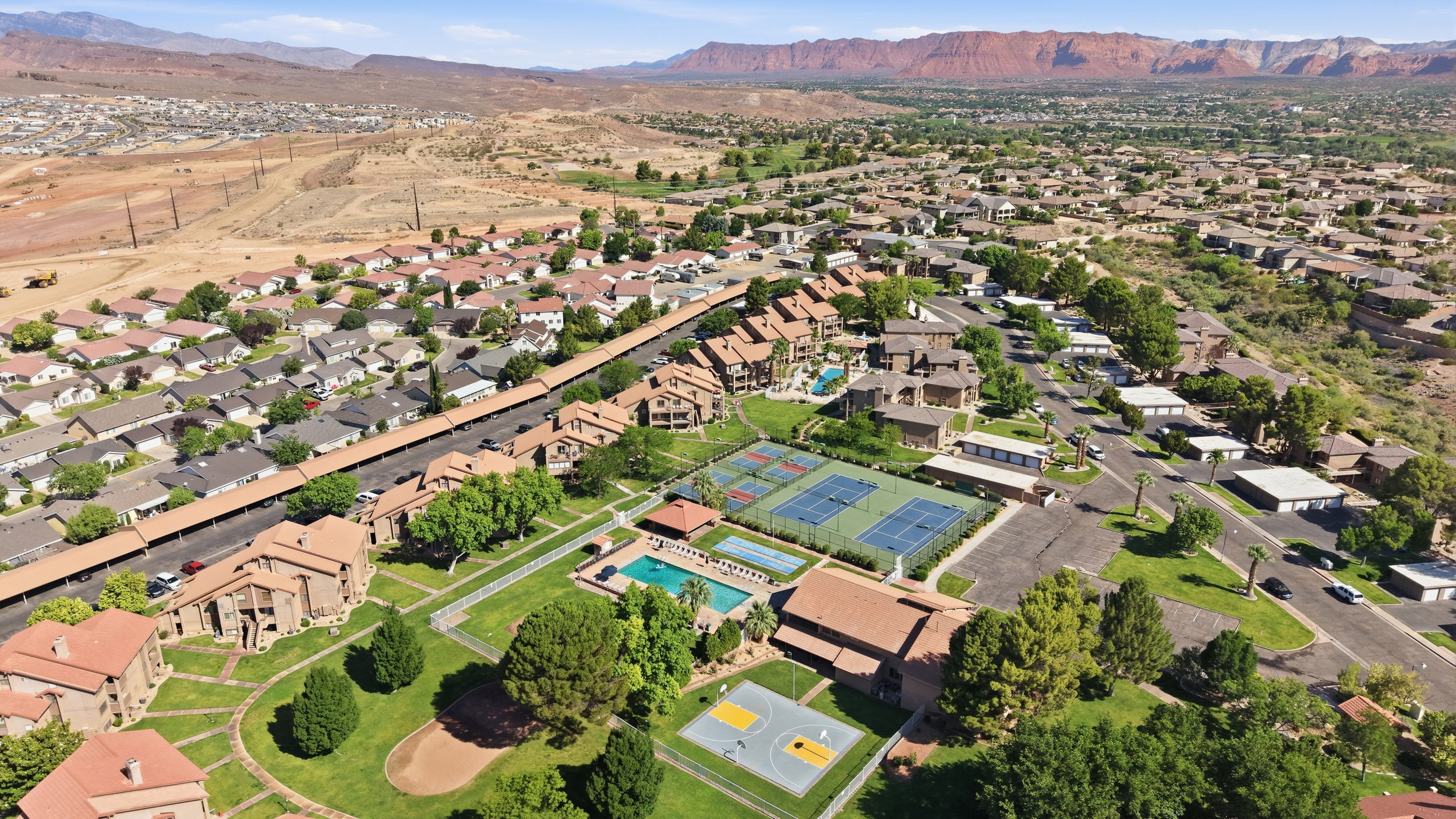 Aerial depiction of a community with residential buildings, swimming pools, tennis courts, and a basketball court