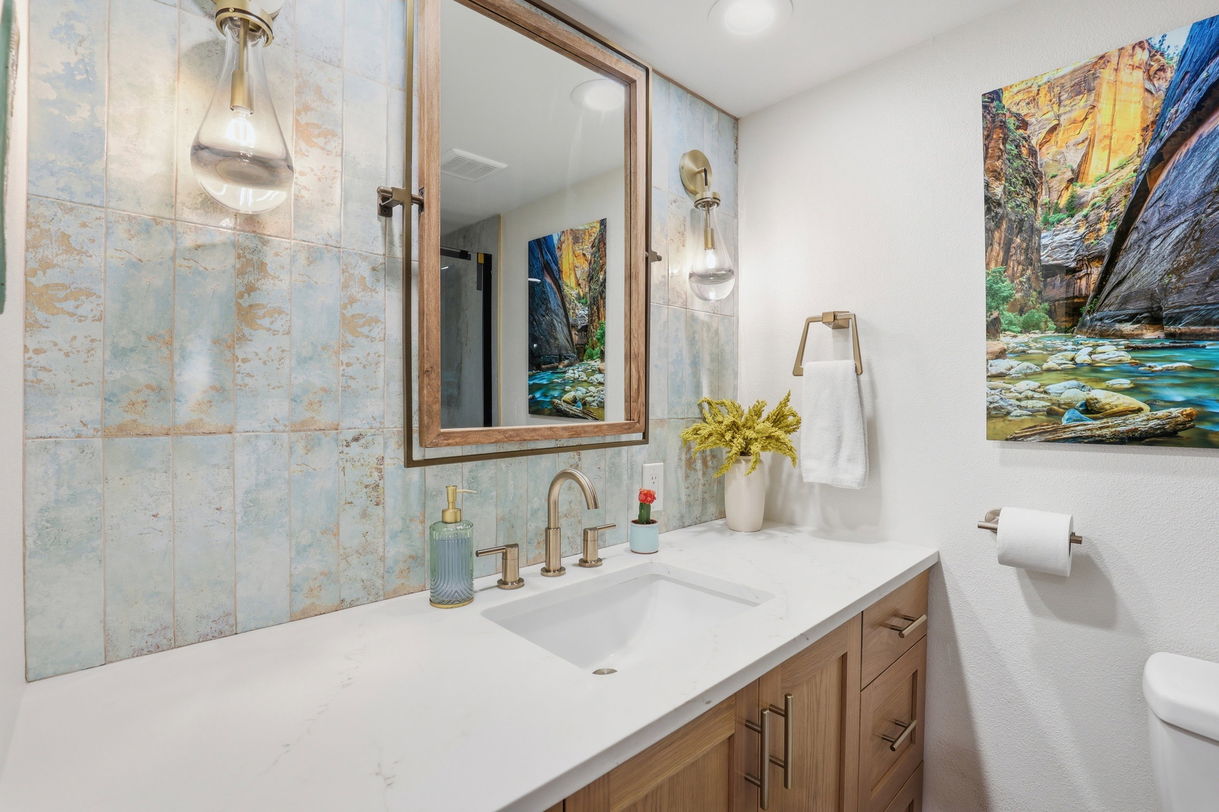 Bathroom vanity featuring a white countertop, an undermount sink, and a gold-finish faucet