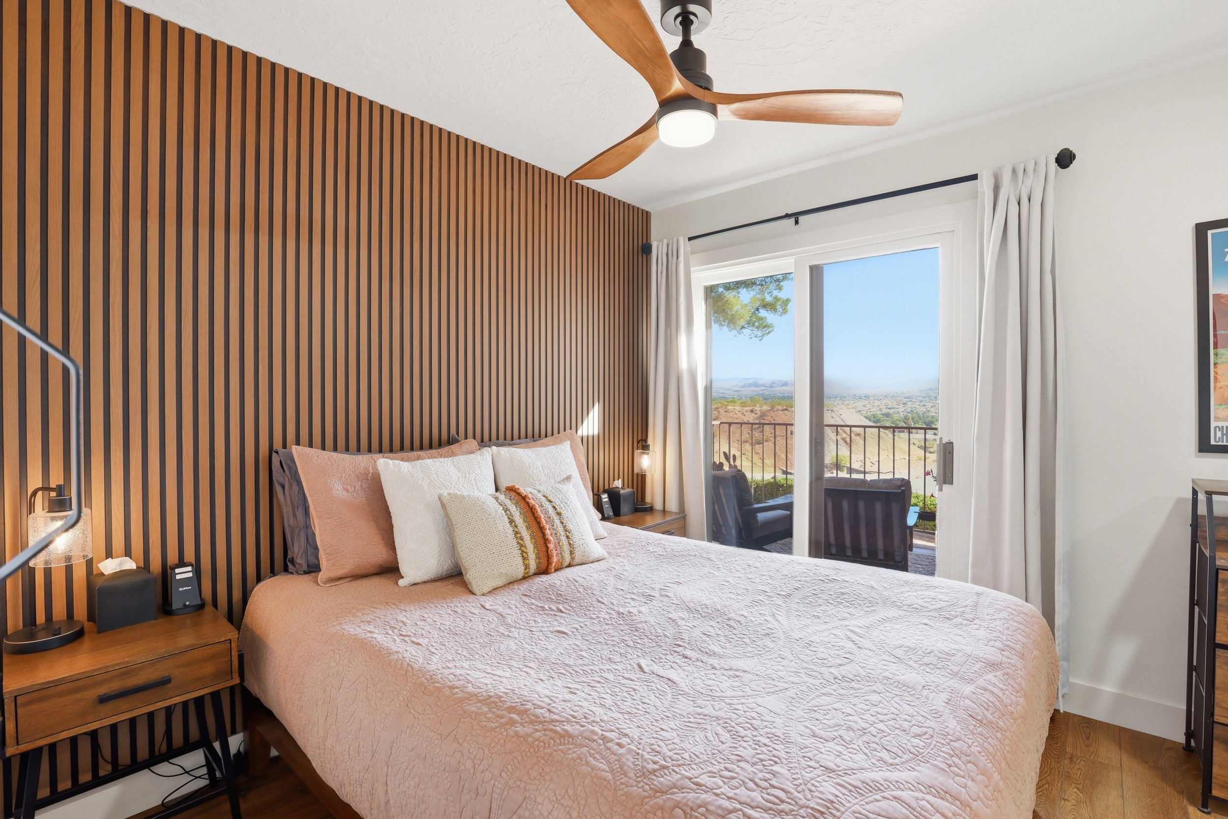 Bedroom featuring a wood-slat accent wall, wood-finish flooring, and a ceiling fan with integrated lighting