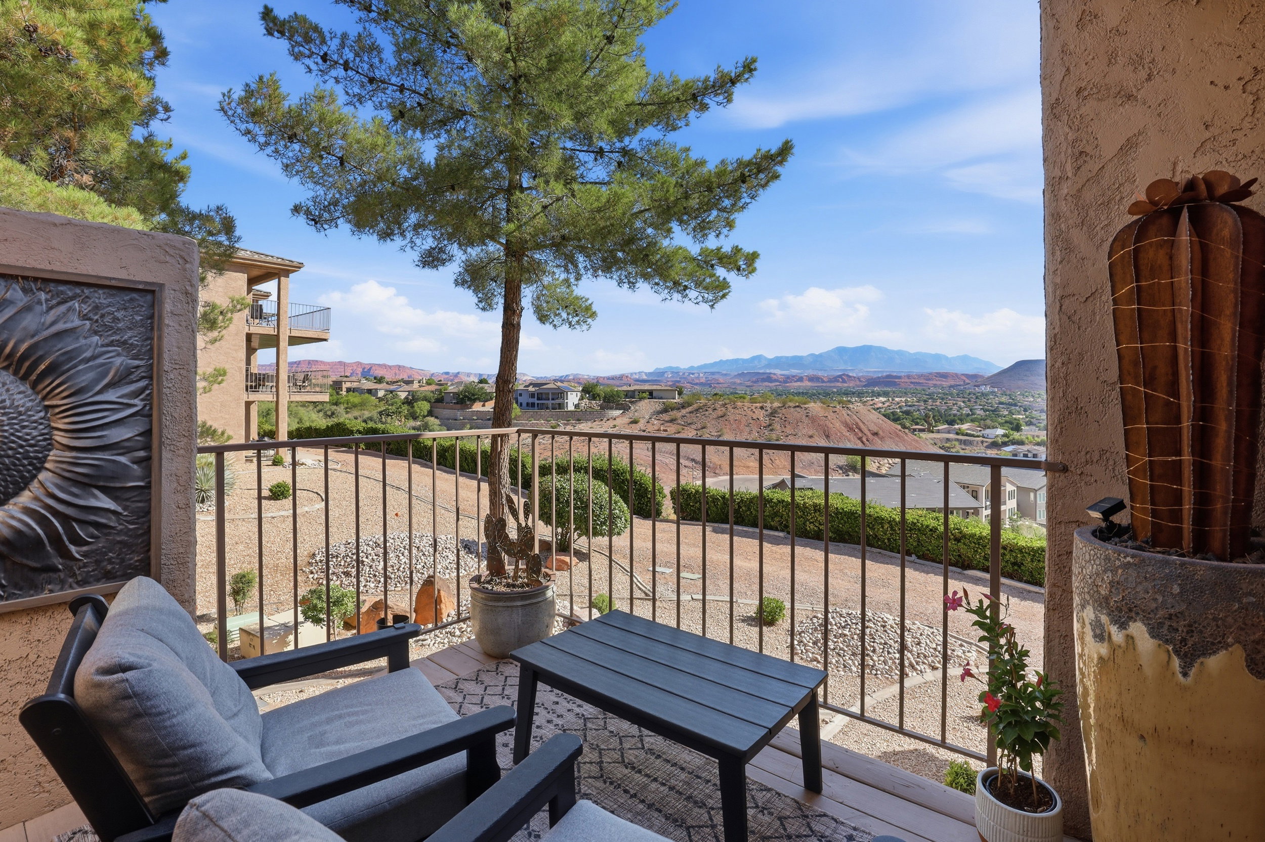 Outdoor terrace with metal railings and a textured wall, offering expansive desert landscape and distant mountain scenery